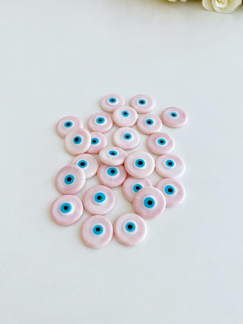 A collection of pink Murano glass evil eye cabochons, each 15mm in diameter, showcasing intricate designs and vibrant colors.