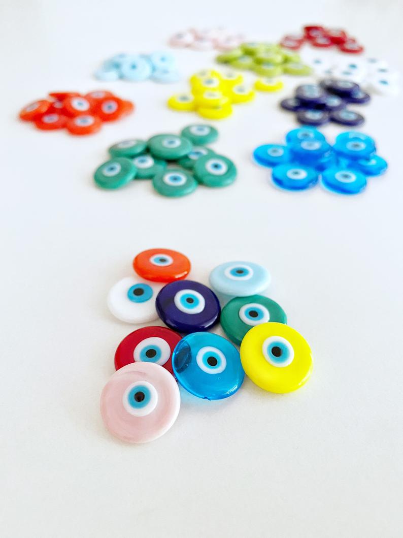 A collection of pink Murano glass evil eye cabochons, each 15mm in diameter, showcasing intricate designs and vibrant colors.