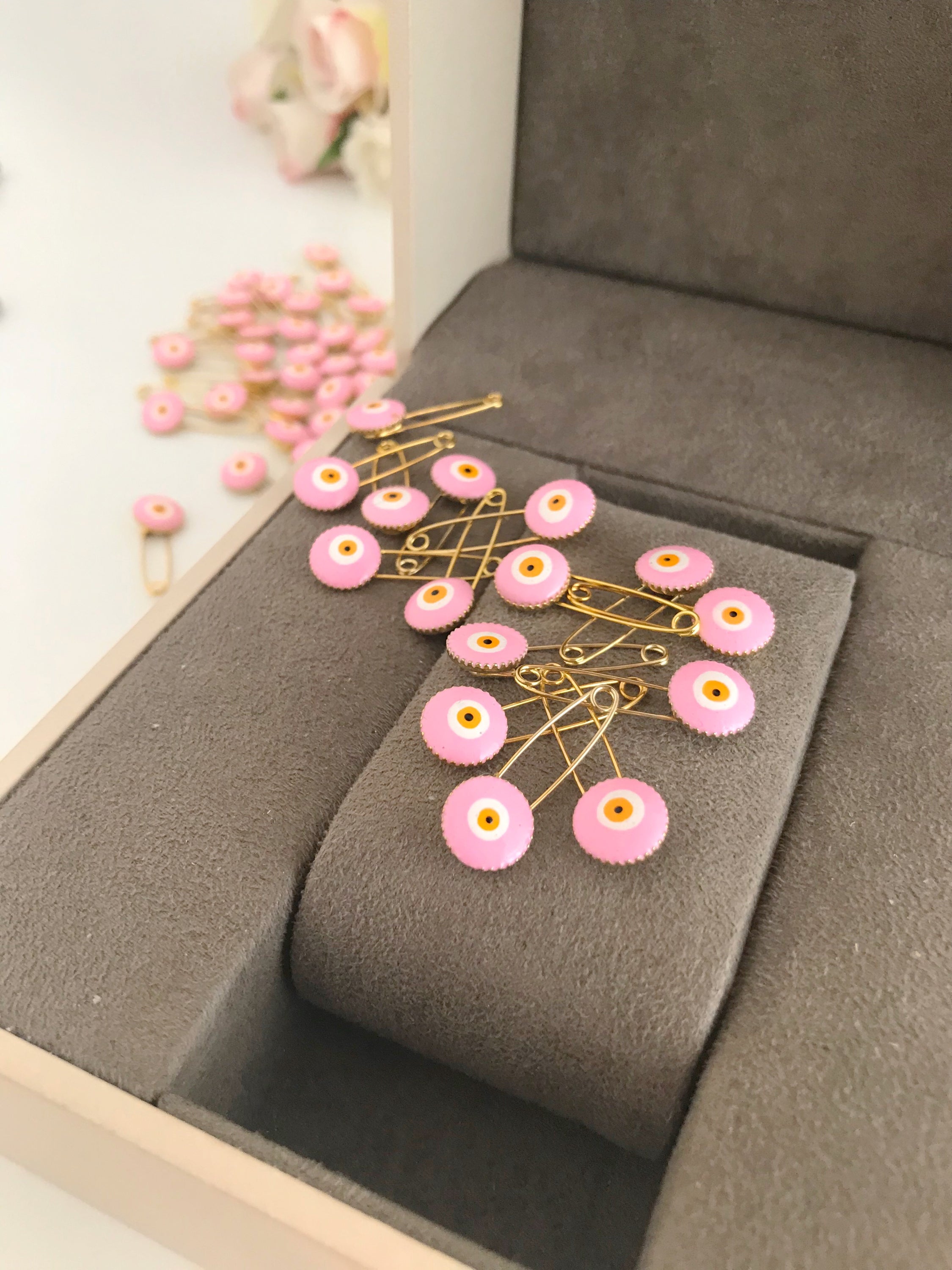 A bulk set of 50 pink evil eye safety pins, featuring a brass construction and an 8mm pink evil eye bead charm, ideal for weddings and baby showers.