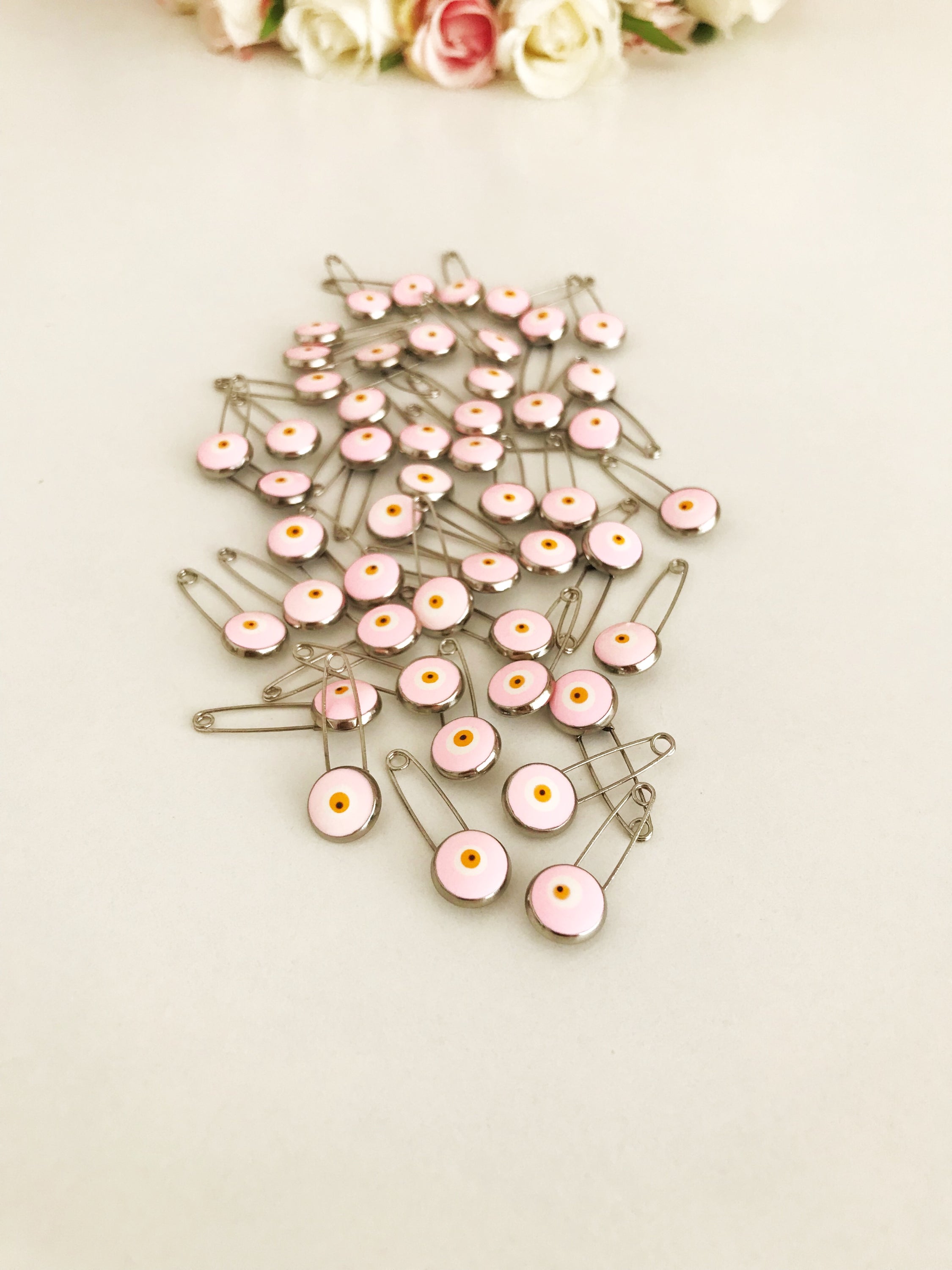 A bulk set of 50 pink evil eye safety pins, featuring a brass construction and an 8mm pink evil eye bead charm, ideal for weddings and baby showers.