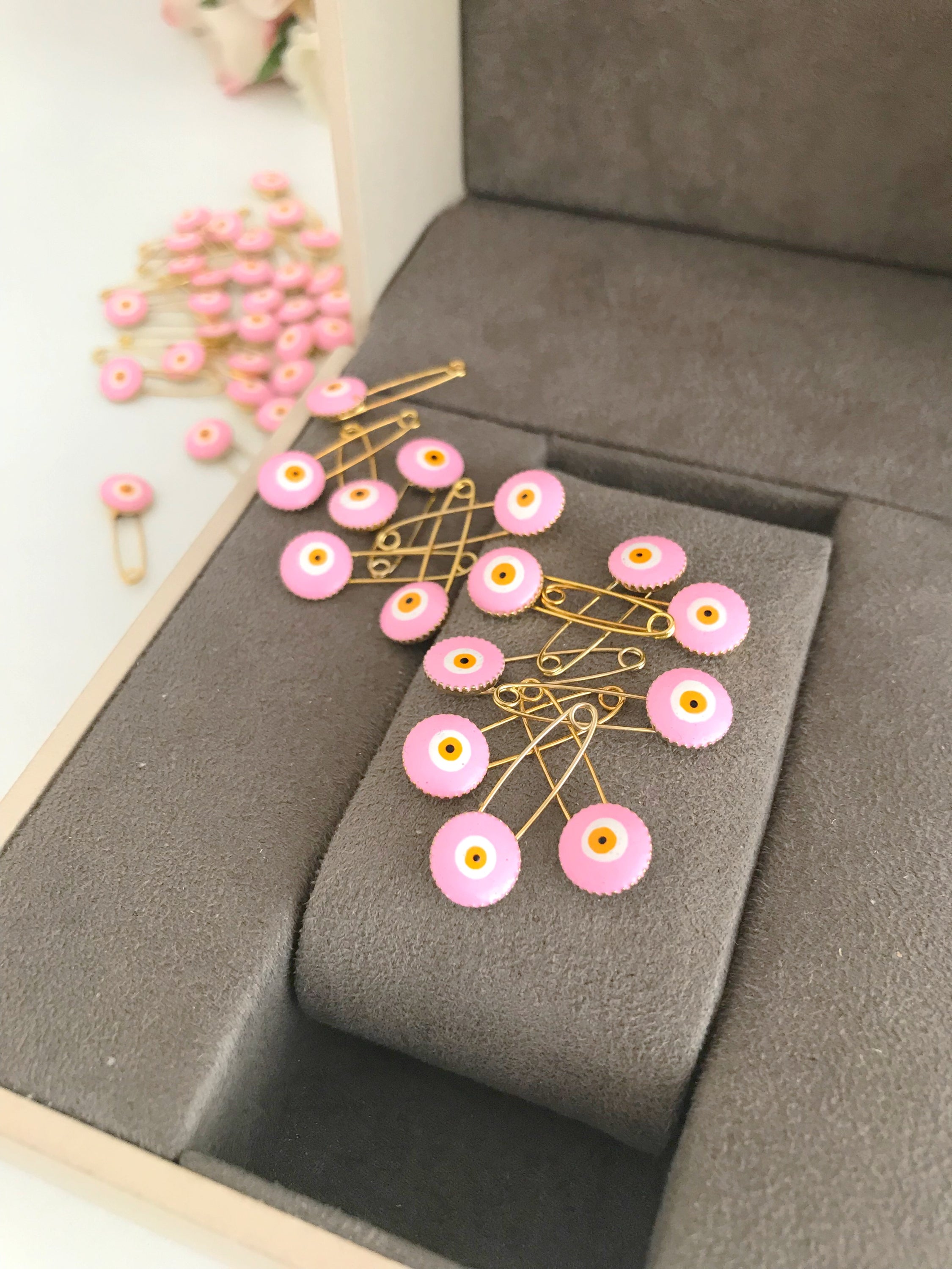 A bulk set of 50 pink evil eye safety pins, featuring a brass construction and an 8mm pink evil eye bead charm, ideal for weddings and baby showers.