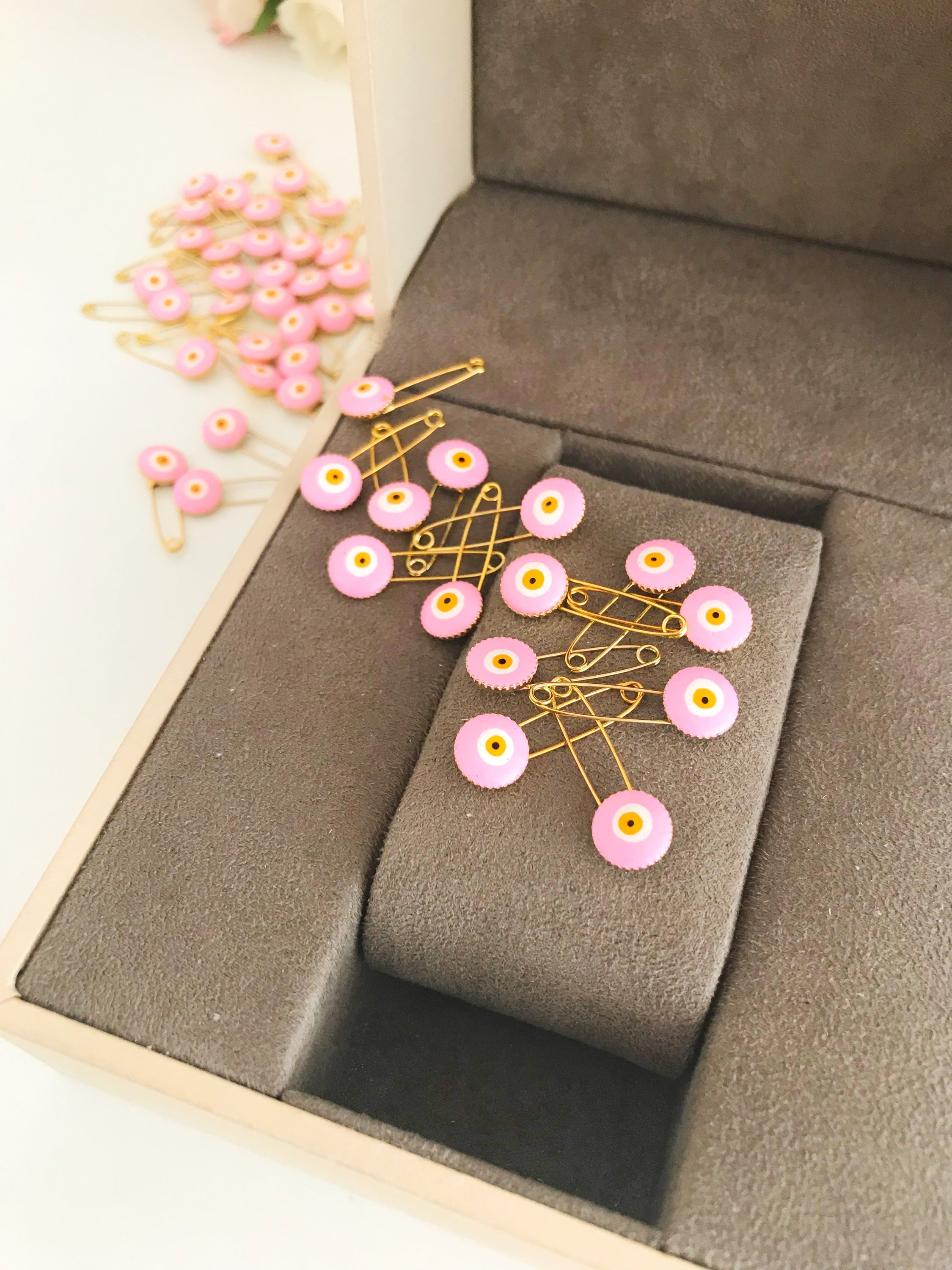 A bulk set of 50 pink evil eye safety pins, featuring a brass construction and an 8mm pink evil eye bead charm, ideal for weddings and baby showers.