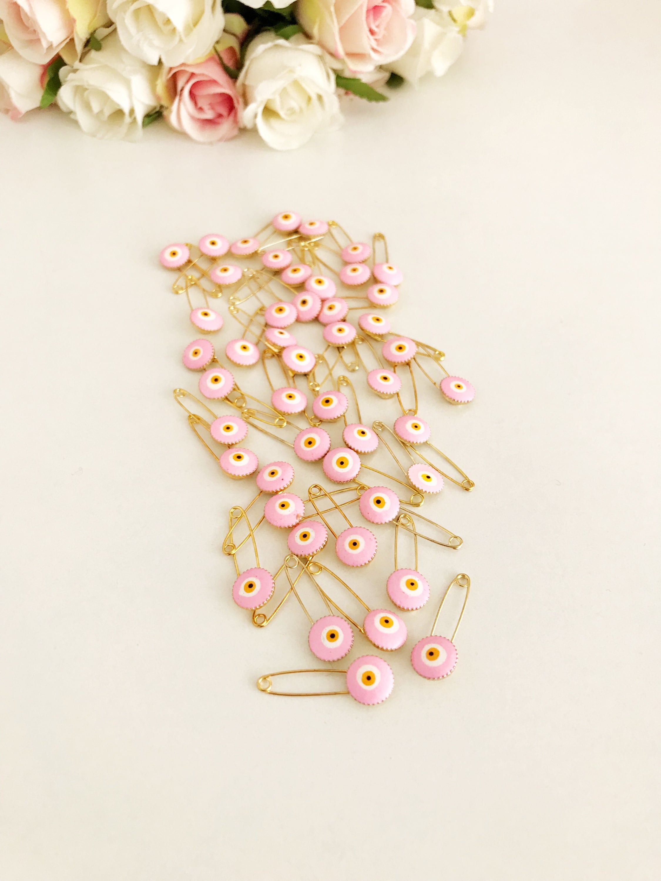 A bulk set of 50 pink evil eye safety pins, featuring a brass construction and an 8mm pink evil eye bead charm, ideal for weddings and baby showers.