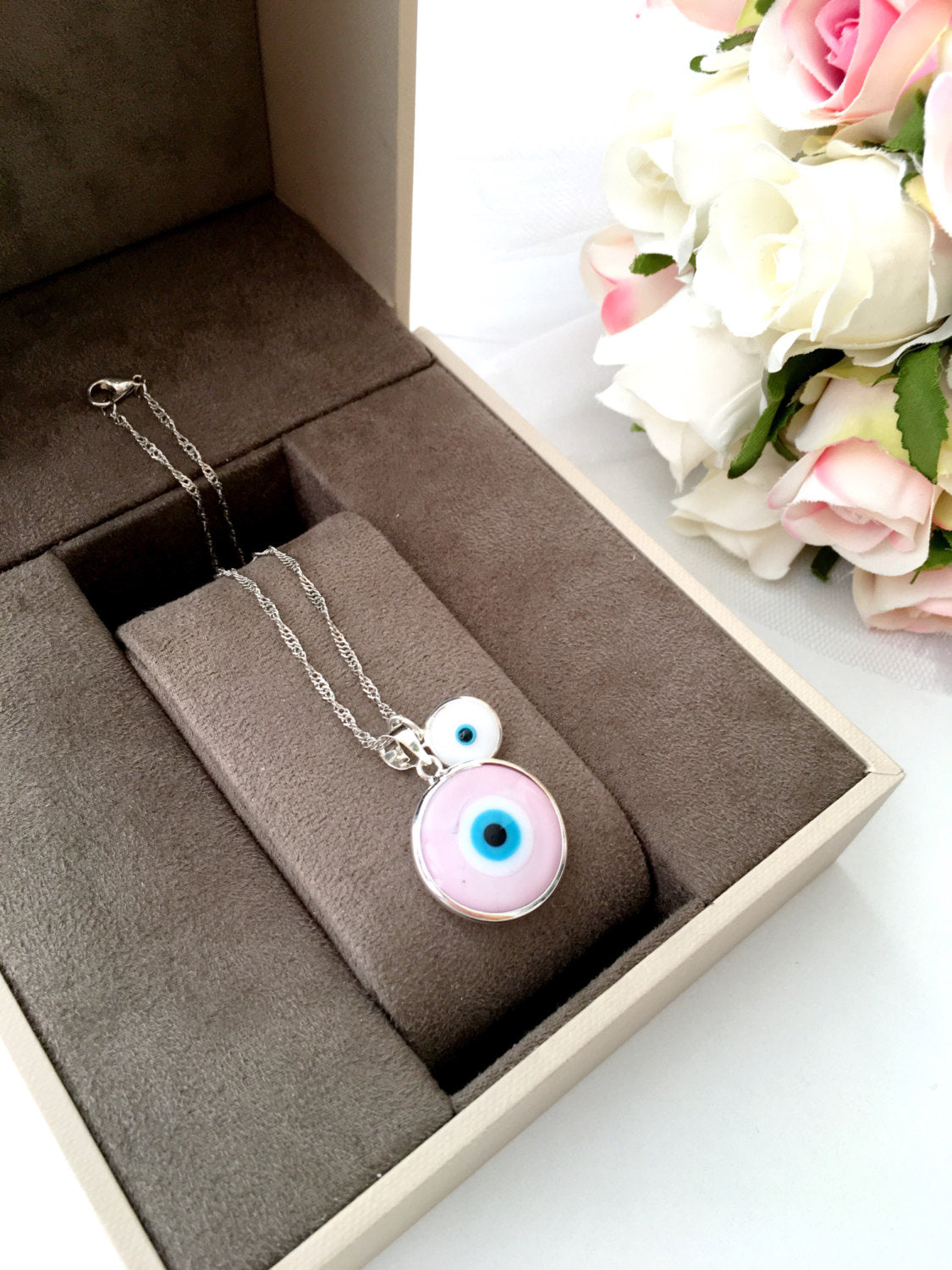 A beautiful Pink Murano Evil Eye Bead Necklace featuring a large pink eye bead and tiny white evil eye beads on a silver plated chain.