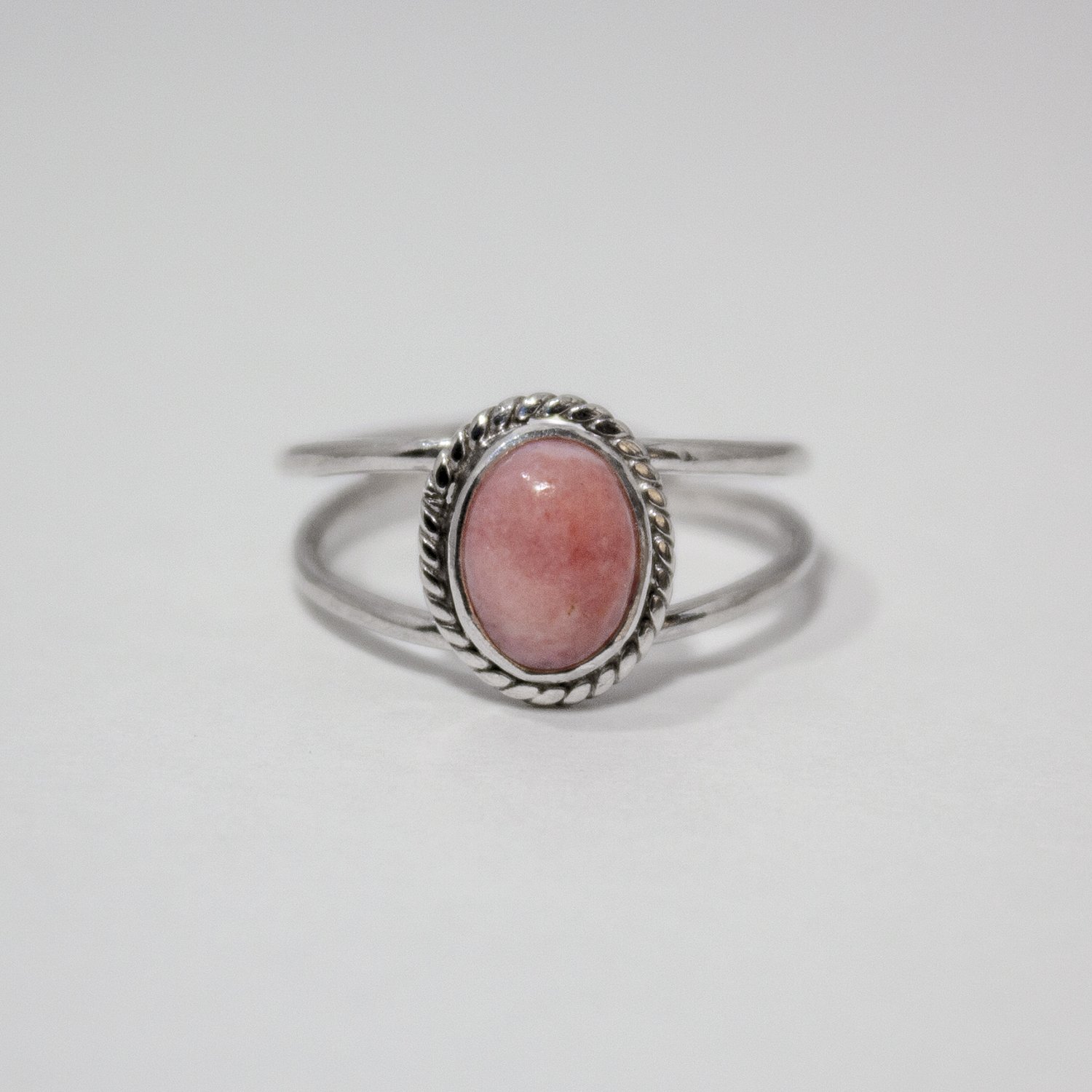 Elegant Pink Opal Oval Double Band Sterling Silver Ring featuring a soft pink gemstone in a twist patterned bezel setting.