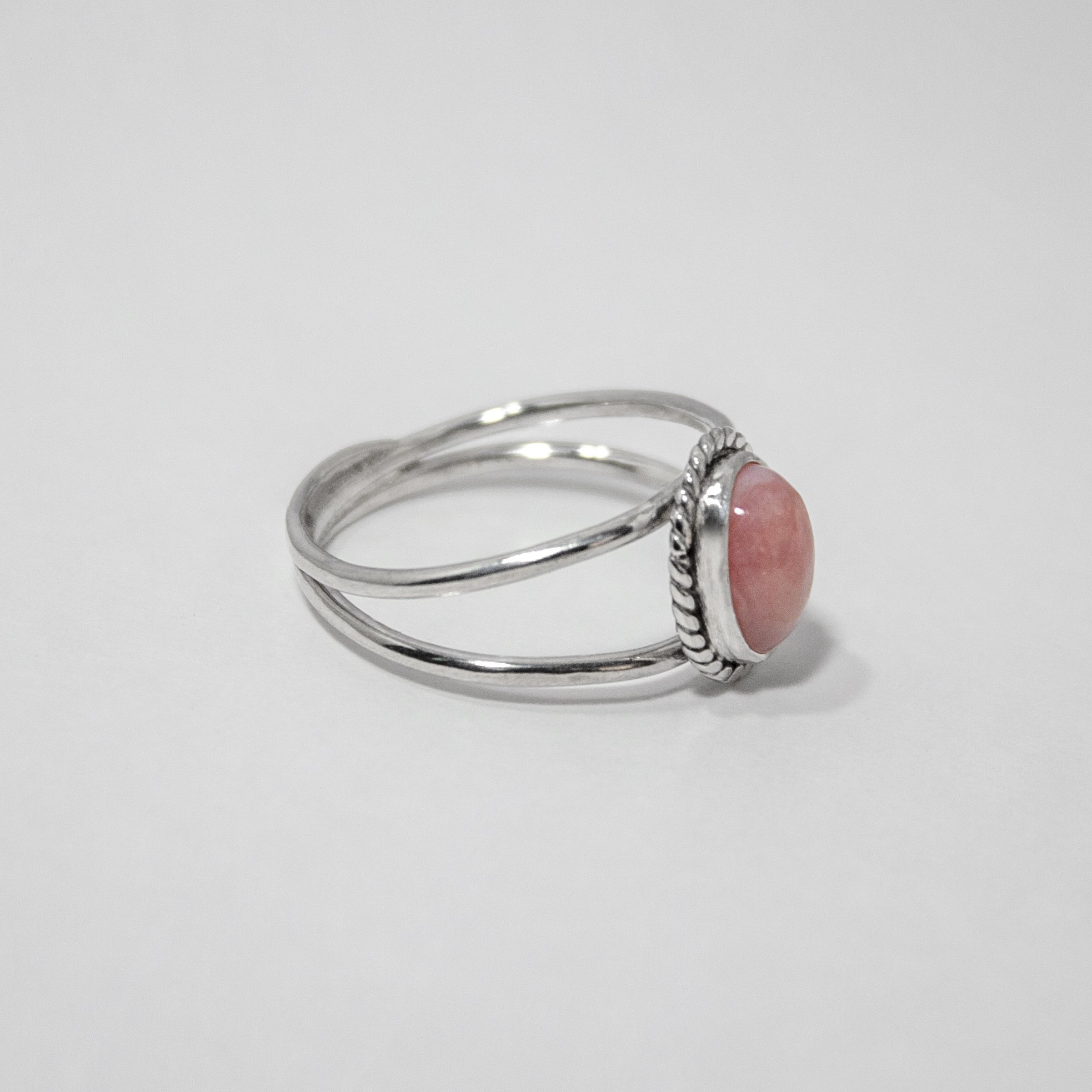 Elegant Pink Opal Oval Double Band Sterling Silver Ring featuring a soft pink gemstone in a twist patterned bezel setting.