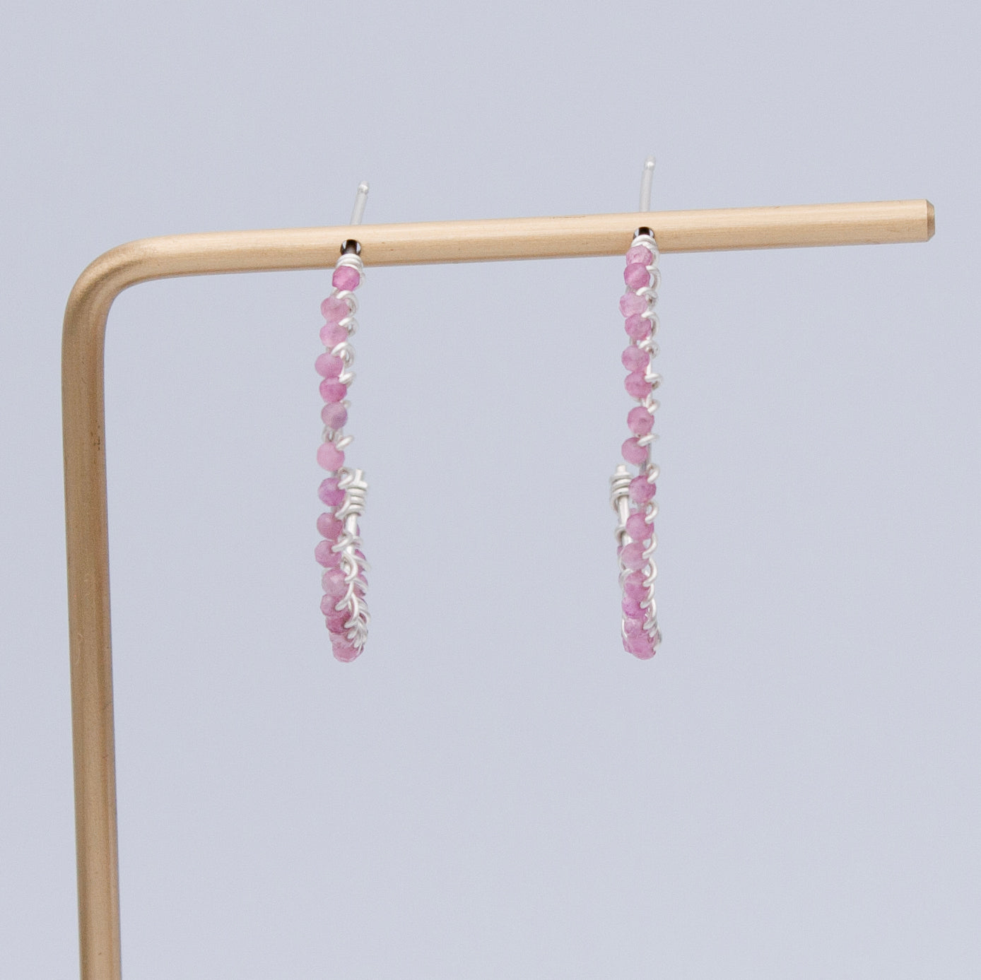 A pair of elegant pink tourmaline beaded sterling silver hoop earrings, featuring 2mm pink tourmaline beads and a 1-inch diameter hoop design.