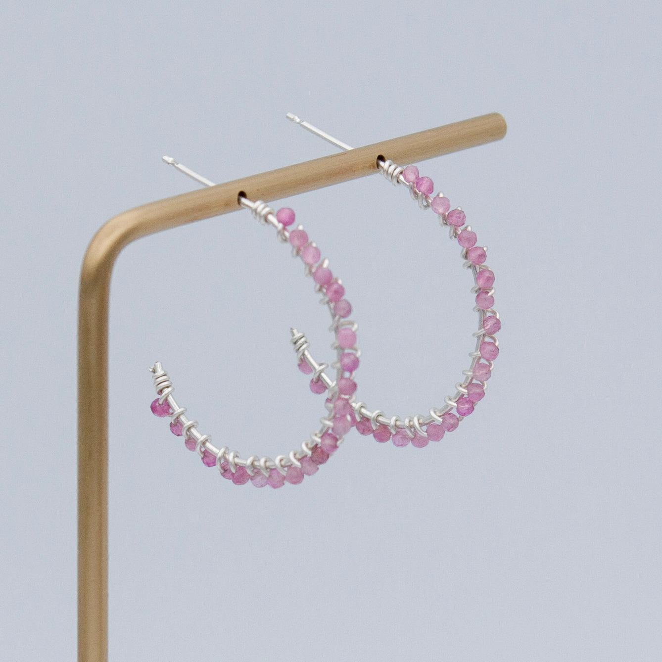 A pair of elegant pink tourmaline beaded sterling silver hoop earrings, featuring 2mm pink tourmaline beads and a 1-inch diameter hoop design.