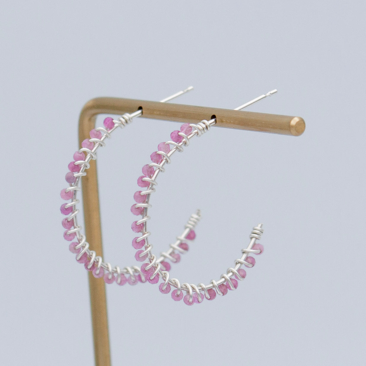 A pair of elegant pink tourmaline beaded sterling silver hoop earrings, featuring 2mm pink tourmaline beads and a 1-inch diameter hoop design.