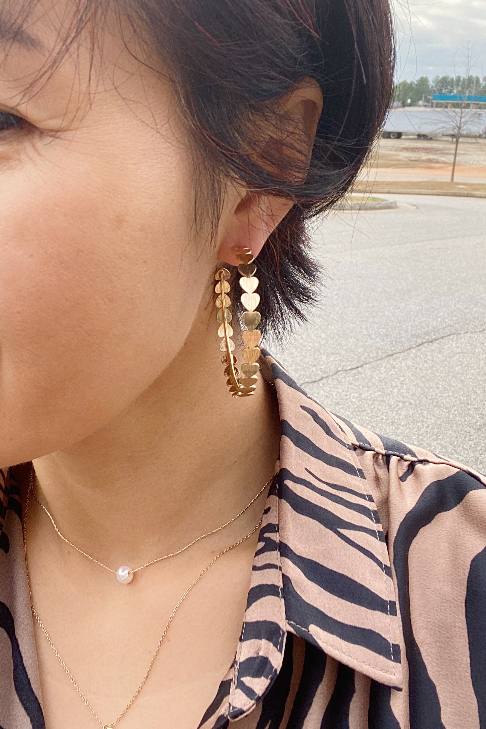 Gold-dipped brass hoop earrings featuring small hearts around the hoop, measuring 2 inches in diameter.