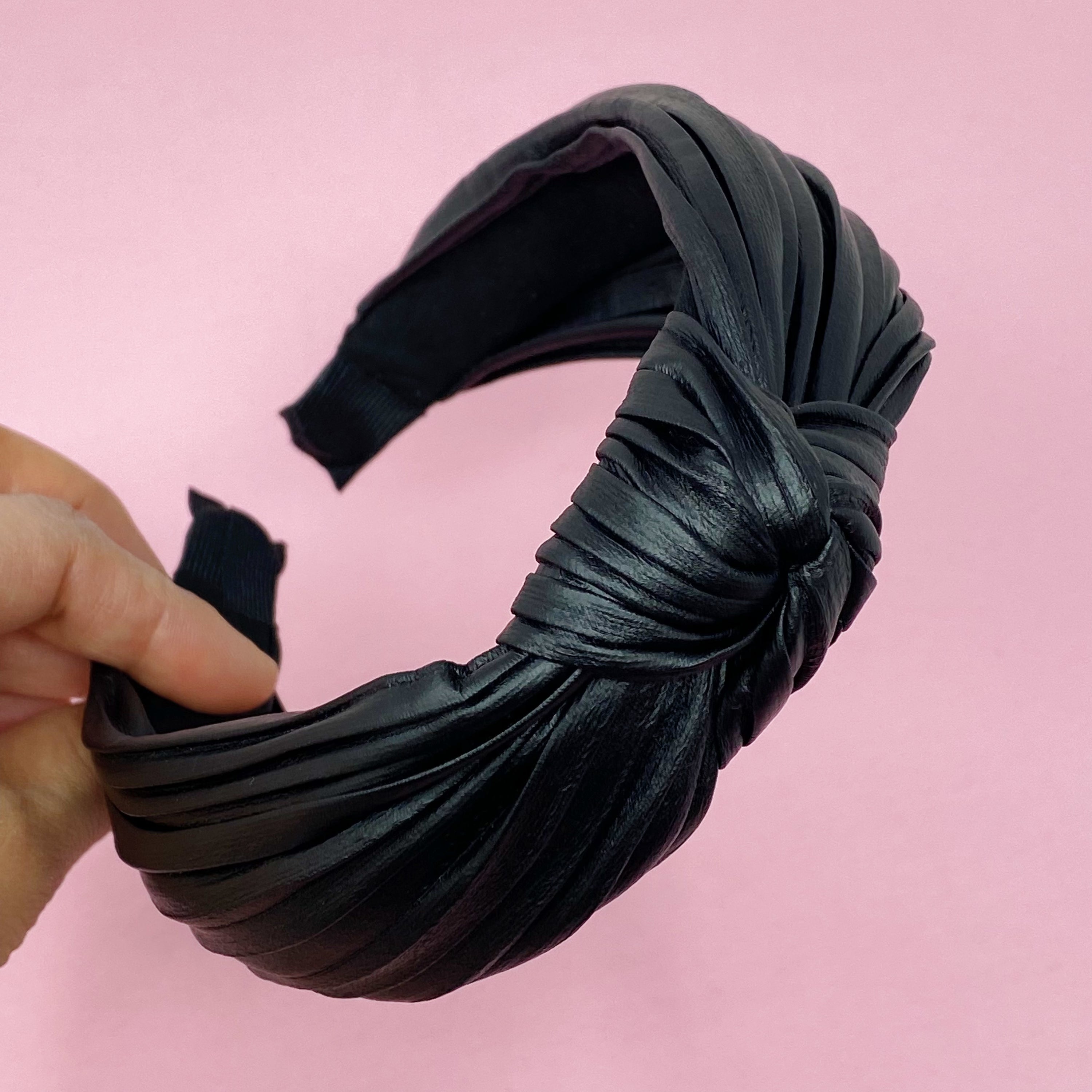 Plenty Pleats Headband featuring leather-like pleated fabric in a chic knotted design, perfect for stylish outfits.