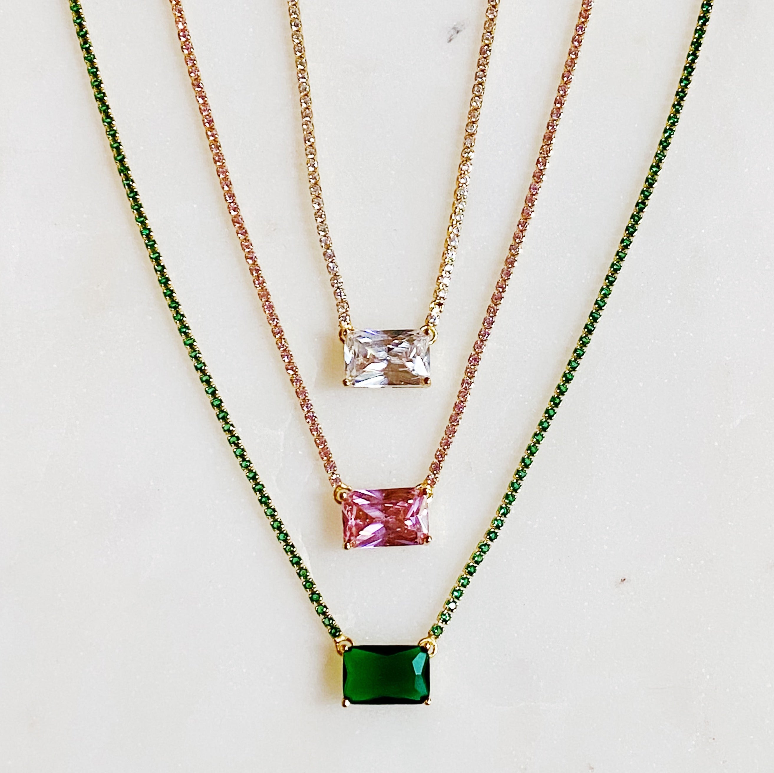 A stunning emerald cut pendant tennis necklace featuring gold-plated brass and sparkling cubic zirconia stones, perfect for elegant occasions.