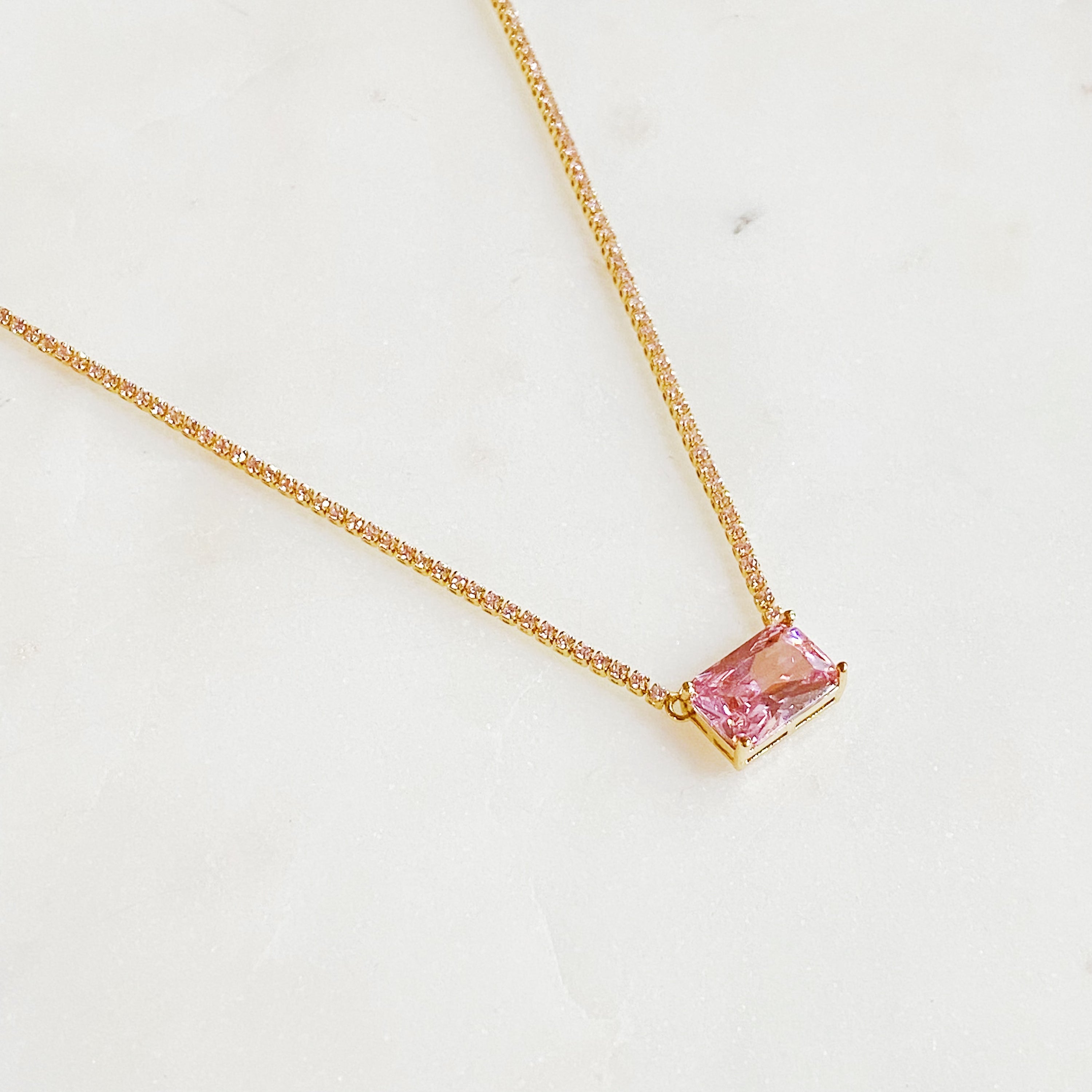 A stunning emerald cut pendant tennis necklace featuring gold-plated brass and sparkling cubic zirconia stones, perfect for elegant occasions.