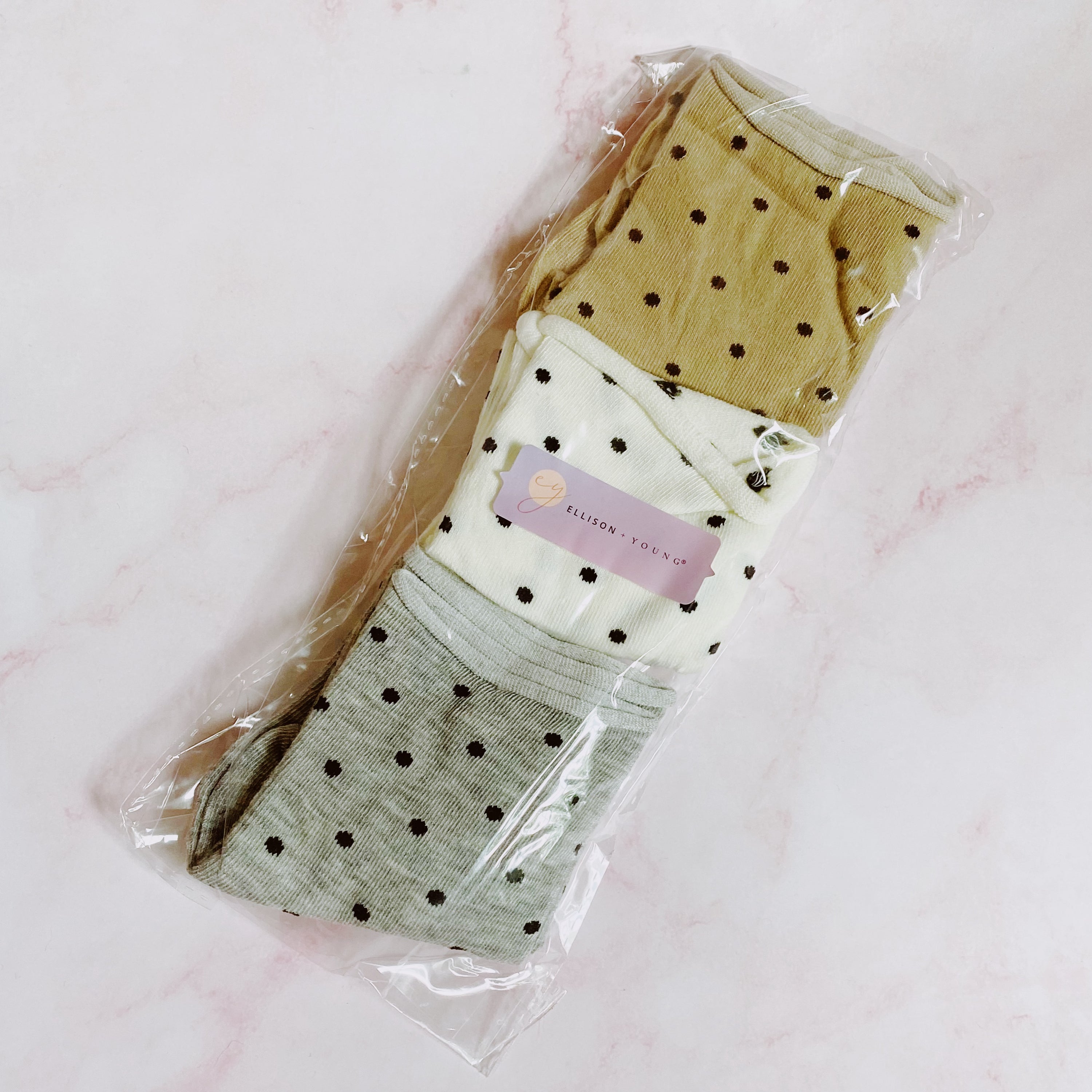 A set of three pairs of Precious Polka Dot Socks featuring colorful polka dots on a soft fabric, neatly packaged in a clear cello bag.