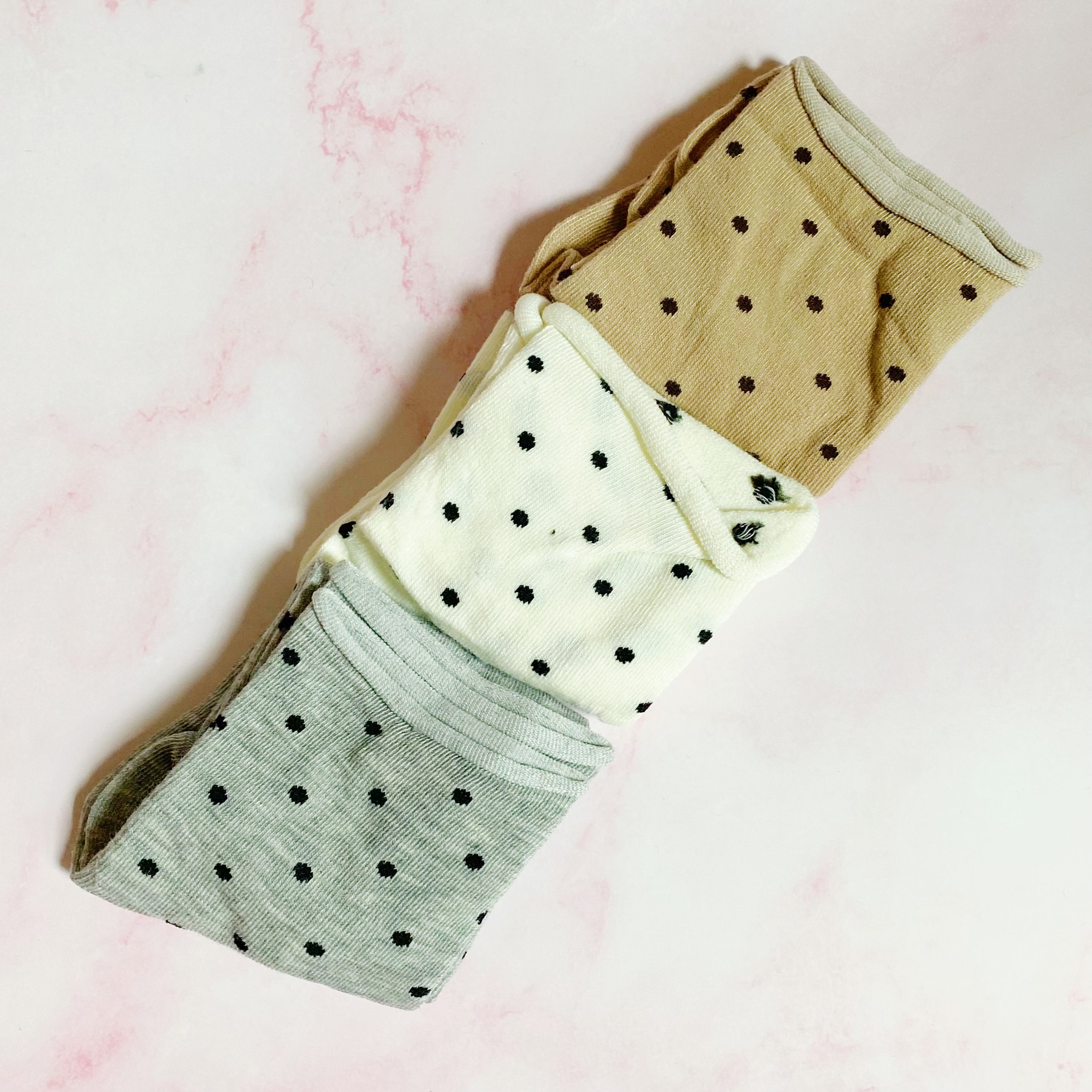 A set of three pairs of Precious Polka Dot Socks featuring colorful polka dots on a soft fabric, neatly packaged in a clear cello bag.