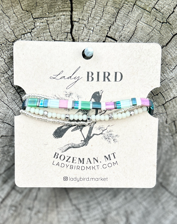 A colorful Preppy Stretchy Tila Bead Bracelet featuring greens, pinks, whites, and silver beads, showcasing its handmade quality and vibrant design.