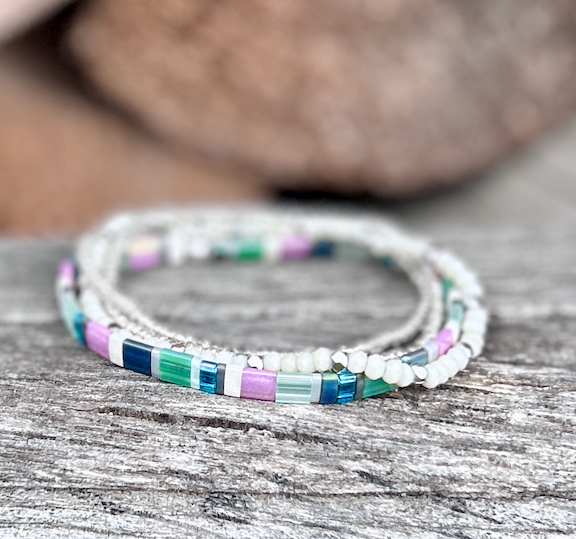 A colorful Preppy Stretchy Tila Bead Bracelet featuring greens, pinks, whites, and silver beads, showcasing its handmade quality and vibrant design.