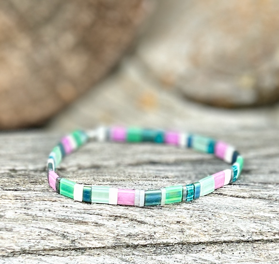 A colorful Preppy Stretchy Tila Bead Bracelet featuring greens, pinks, whites, and silver beads, showcasing its handmade quality and vibrant design.