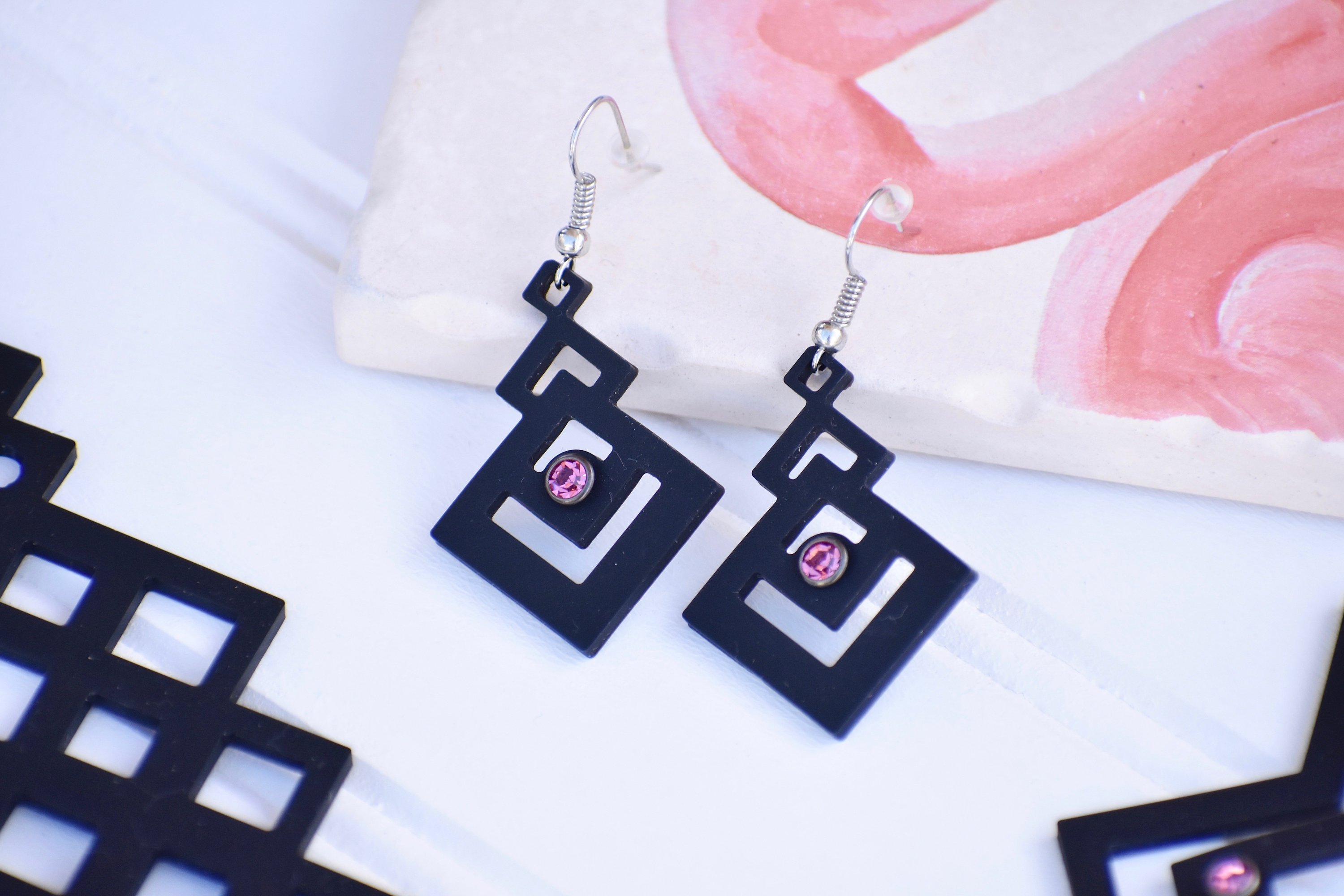 A pair of elegant Pretty Earrings displayed in a velvet pouch, showcasing their unique design and lightweight features.