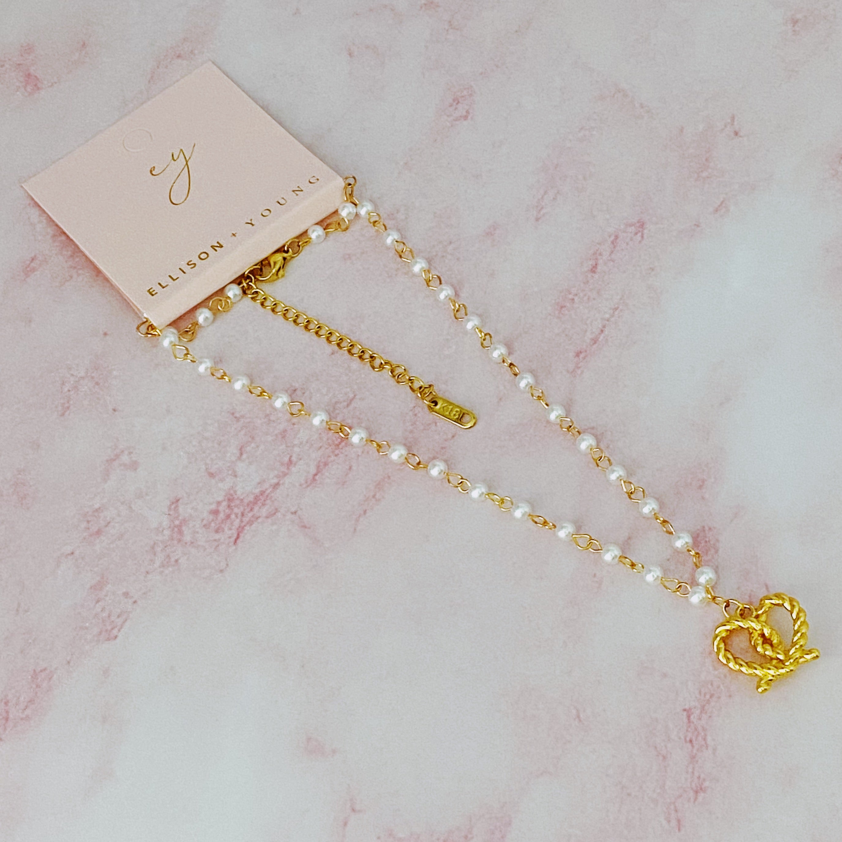 A stylish Pretzel Love Pendant Necklace featuring a heart-shaped pretzel pendant with a pearl mix chain, elegantly crafted in gold plating.