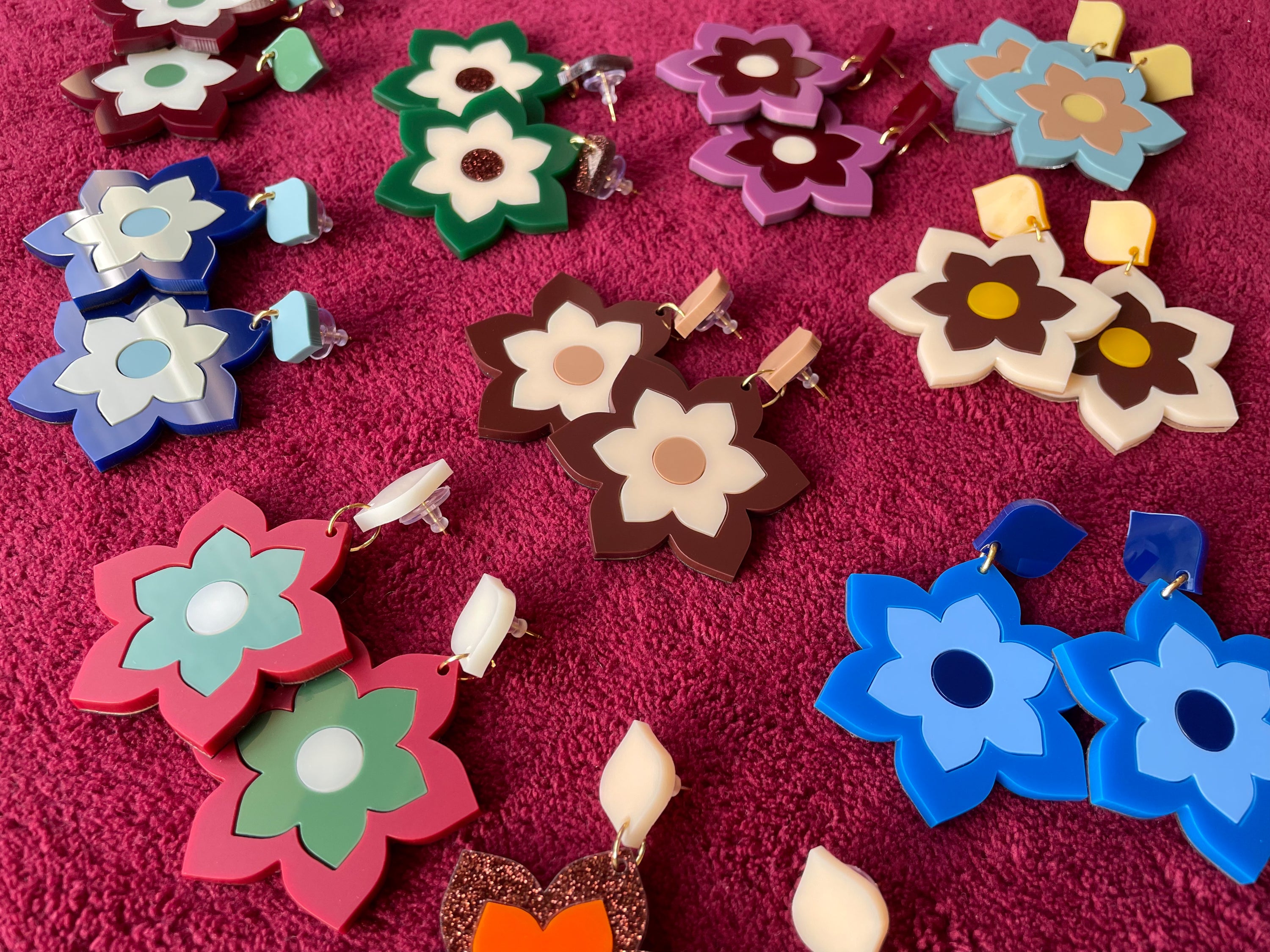 A pair of Prudence Earrings and a matching brooch, showcasing vibrant colors and intricate laser cut acrylic designs inspired by 1960s fashion.