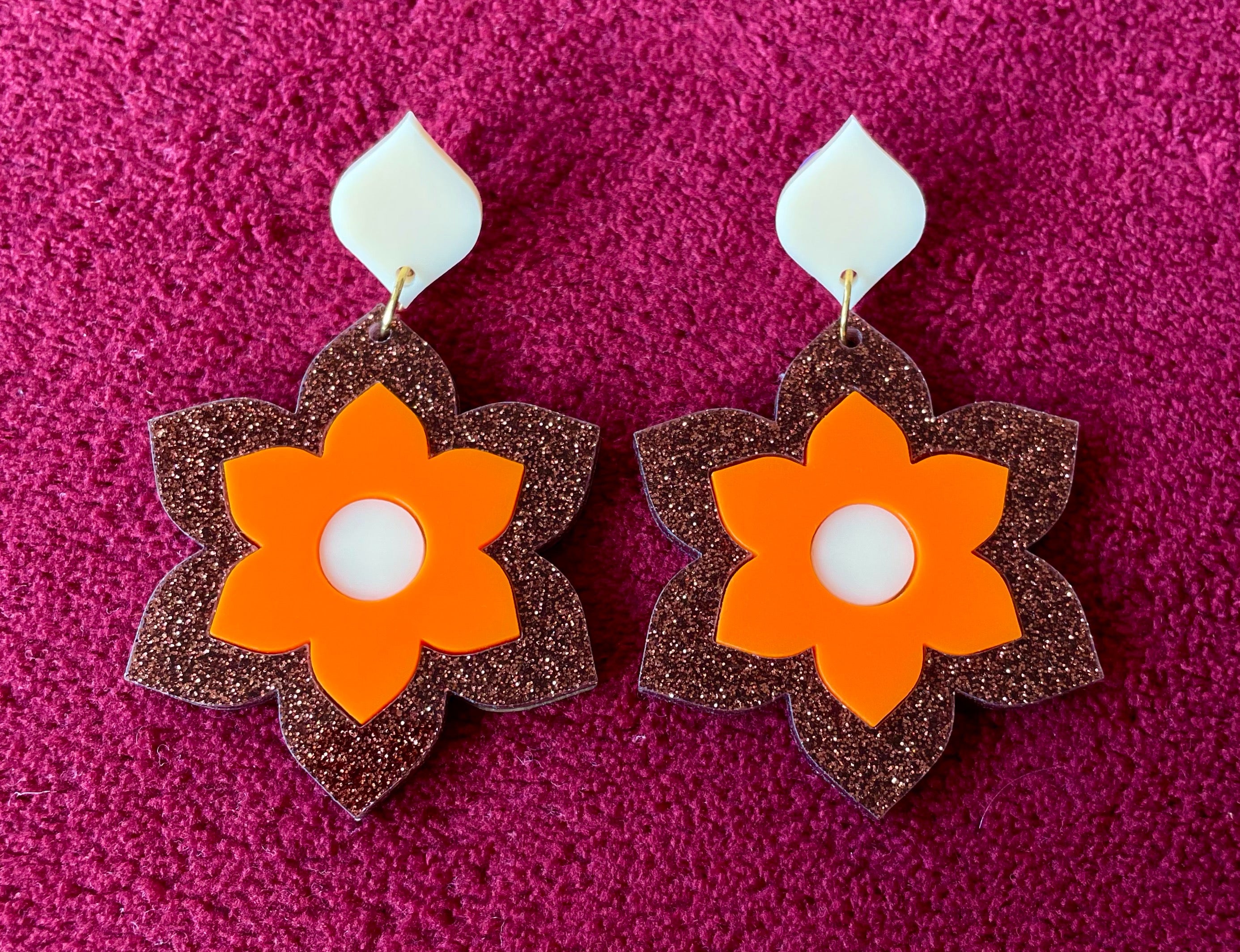 A pair of Prudence Earrings and a matching brooch, showcasing vibrant colors and intricate laser cut acrylic designs inspired by 1960s fashion.