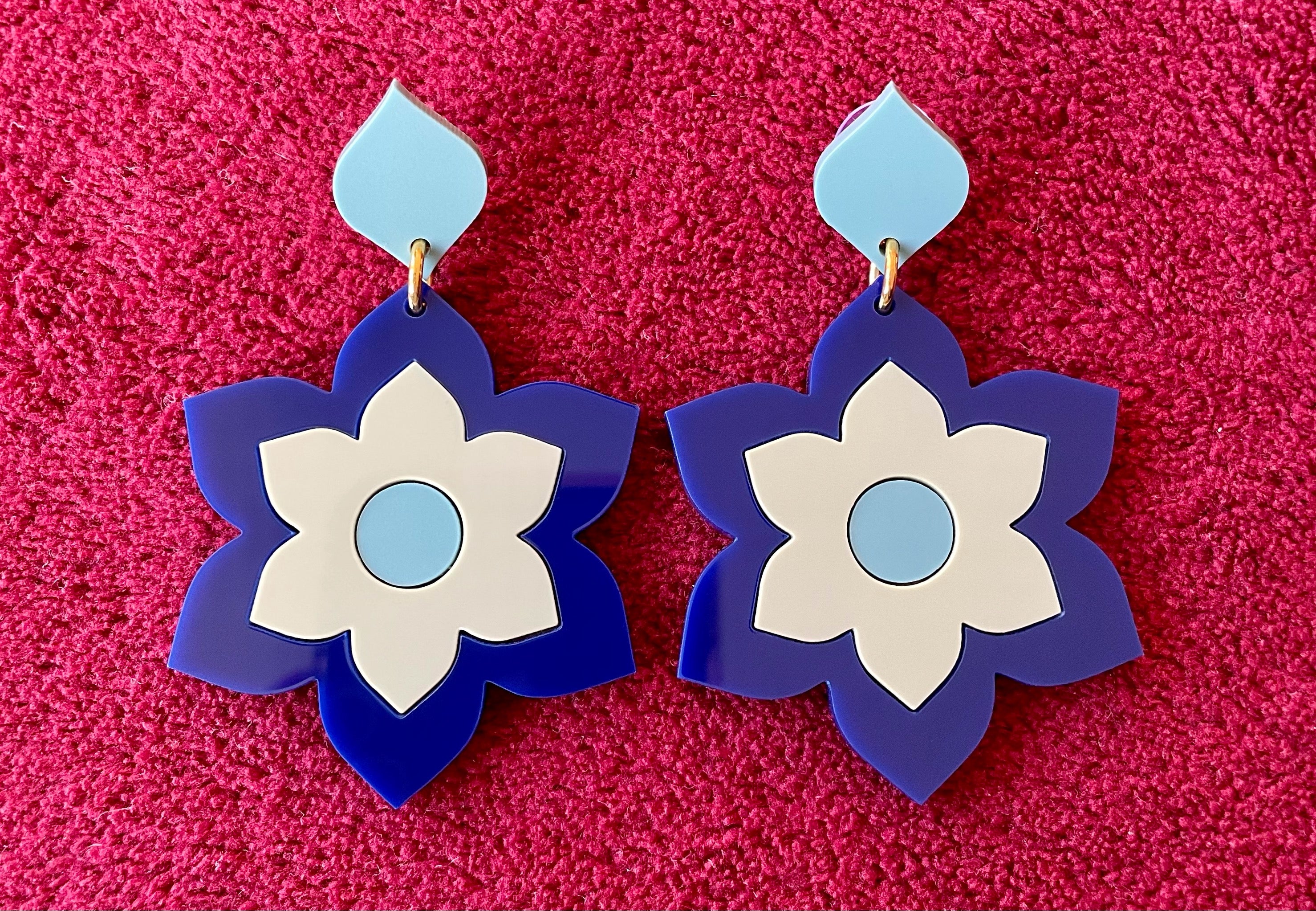 A pair of Prudence Earrings and a matching brooch, showcasing vibrant colors and intricate laser cut acrylic designs inspired by 1960s fashion.