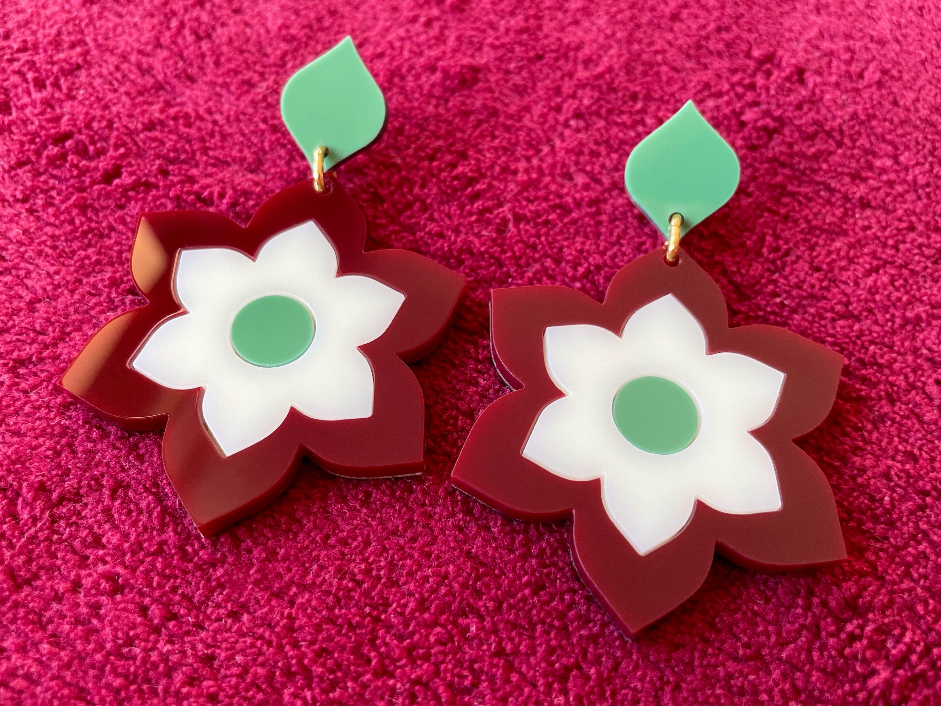 A pair of Prudence Earrings and a matching brooch, showcasing vibrant colors and intricate laser cut acrylic designs inspired by 1960s fashion.