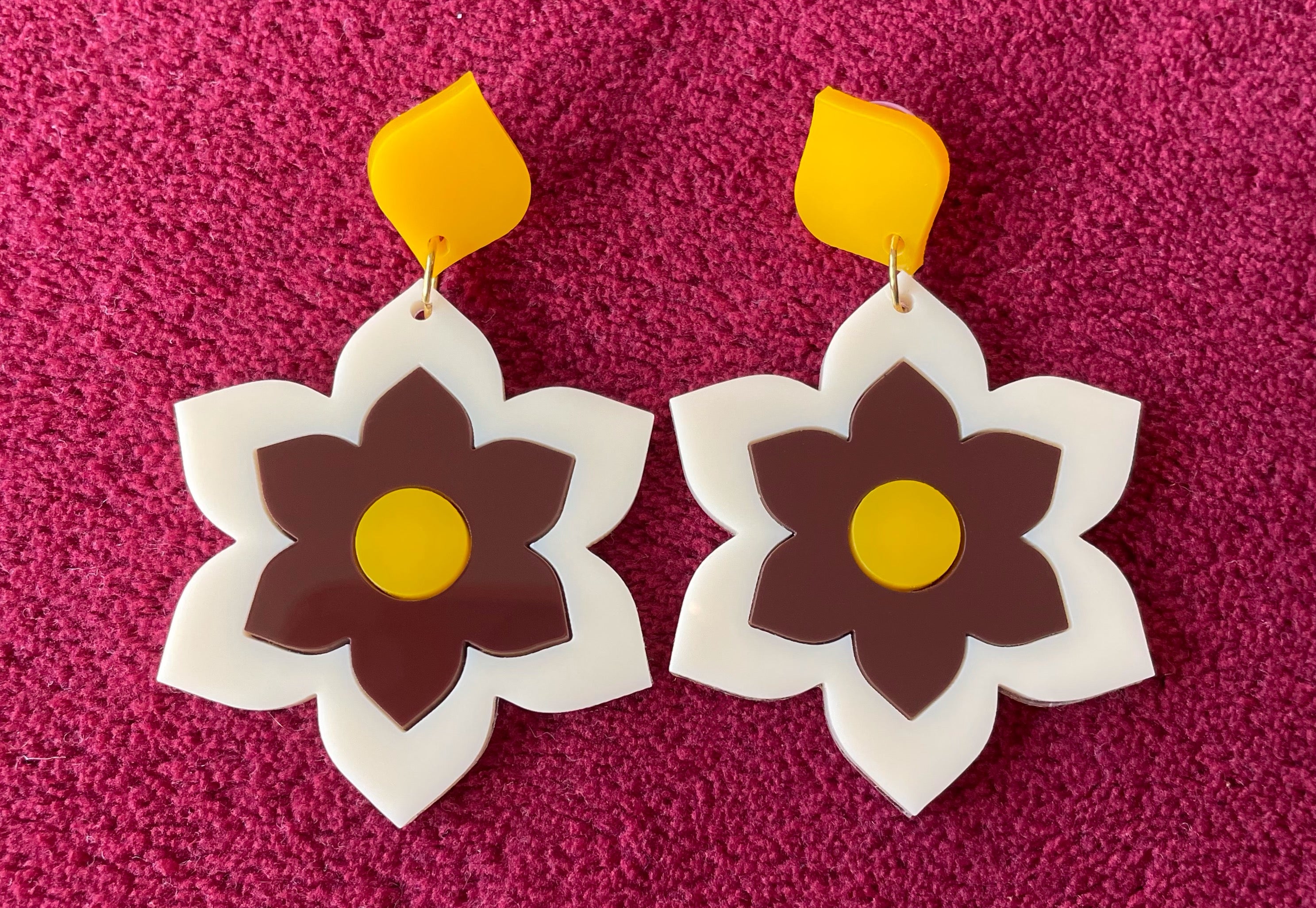 A pair of Prudence Earrings and a matching brooch, showcasing vibrant colors and intricate laser cut acrylic designs inspired by 1960s fashion.