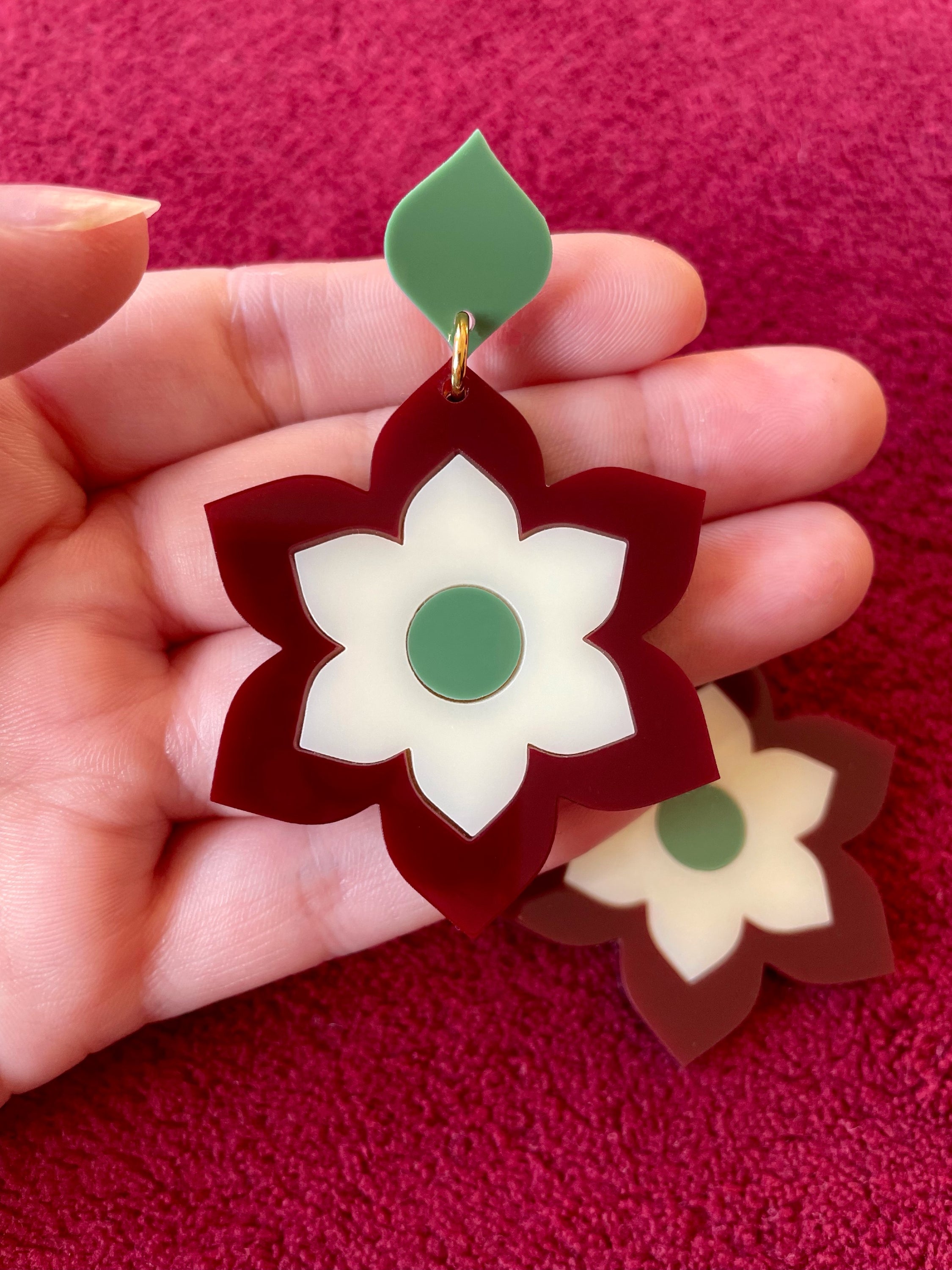 A pair of Prudence Earrings and a matching brooch, showcasing vibrant colors and intricate laser cut acrylic designs inspired by 1960s fashion.