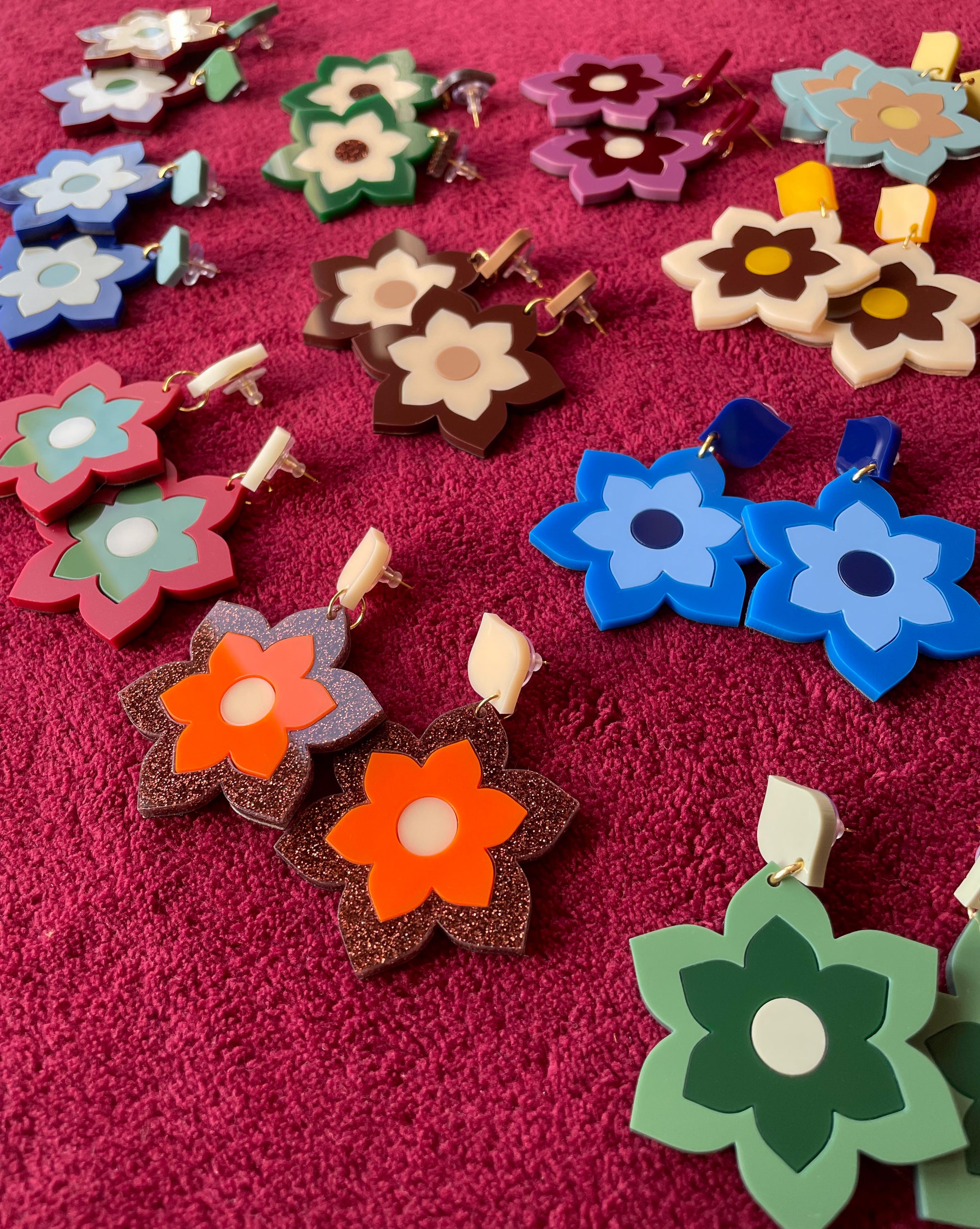 A pair of Prudence Earrings and a matching brooch, showcasing vibrant colors and intricate laser cut acrylic designs inspired by 1960s fashion.