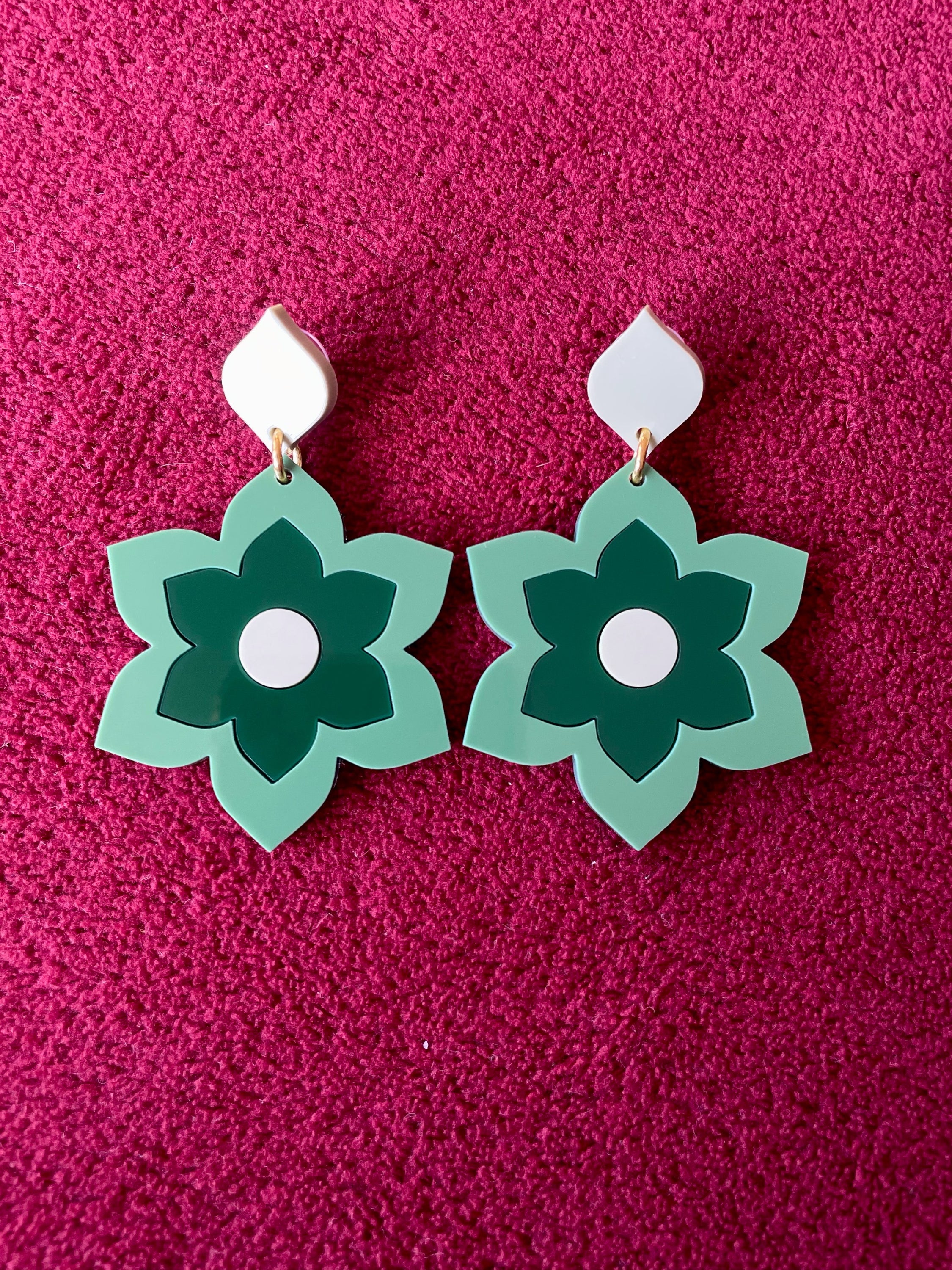 A pair of Prudence Earrings and a matching brooch, showcasing vibrant colors and intricate laser cut acrylic designs inspired by 1960s fashion.