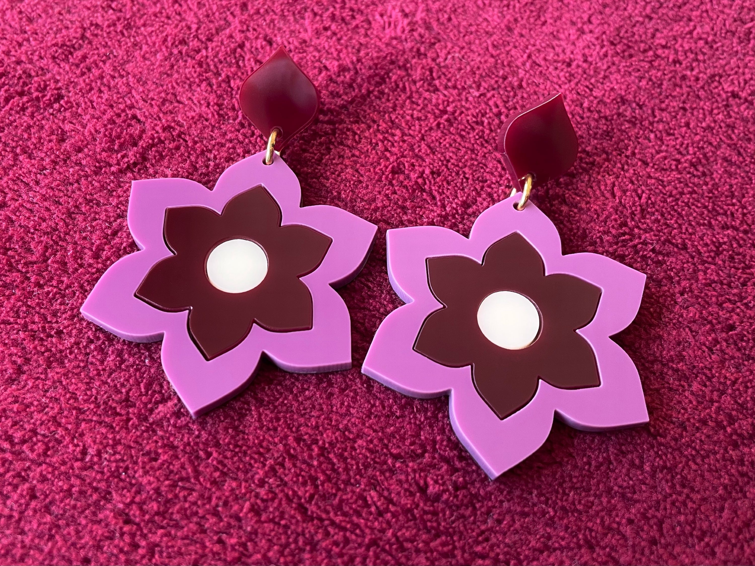 A pair of Prudence Earrings and a matching brooch, showcasing vibrant colors and intricate laser cut acrylic designs inspired by 1960s fashion.