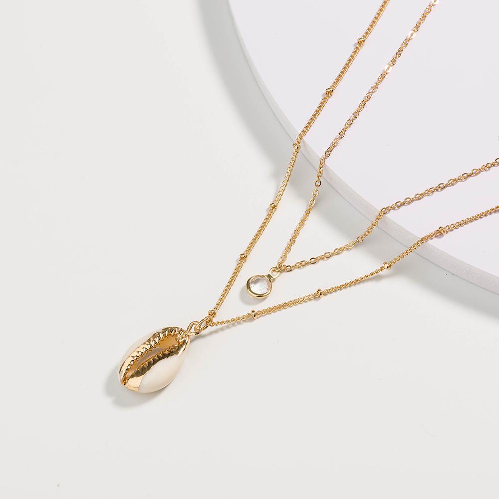 Gold puka shell necklace with crystal pendant on a dainty gold plated chain, elegantly displayed in a gift box.