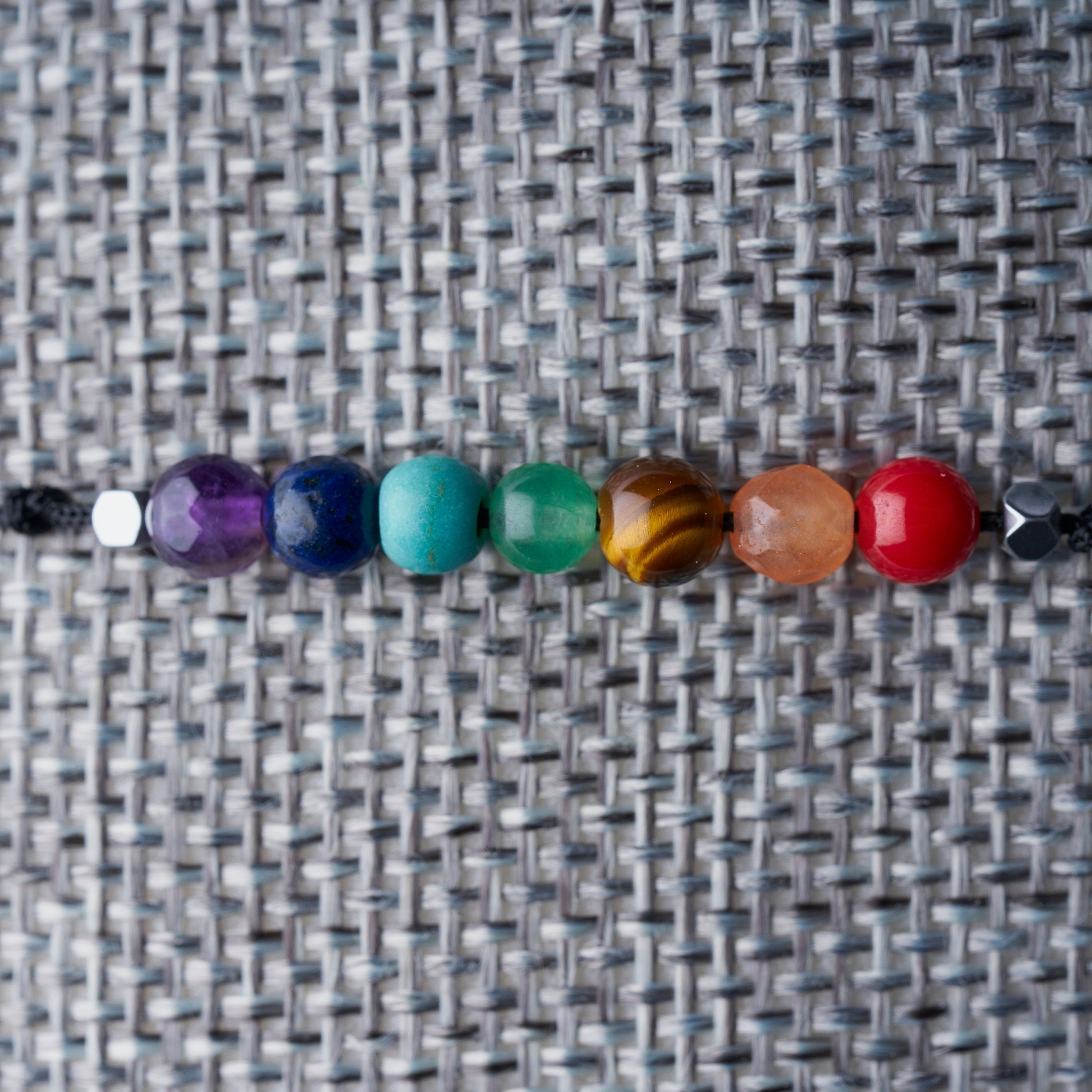 Pulsera de 7 chakras ajustable con piedras naturales en hilo negro, ideal para meditación y equilibrio energético.