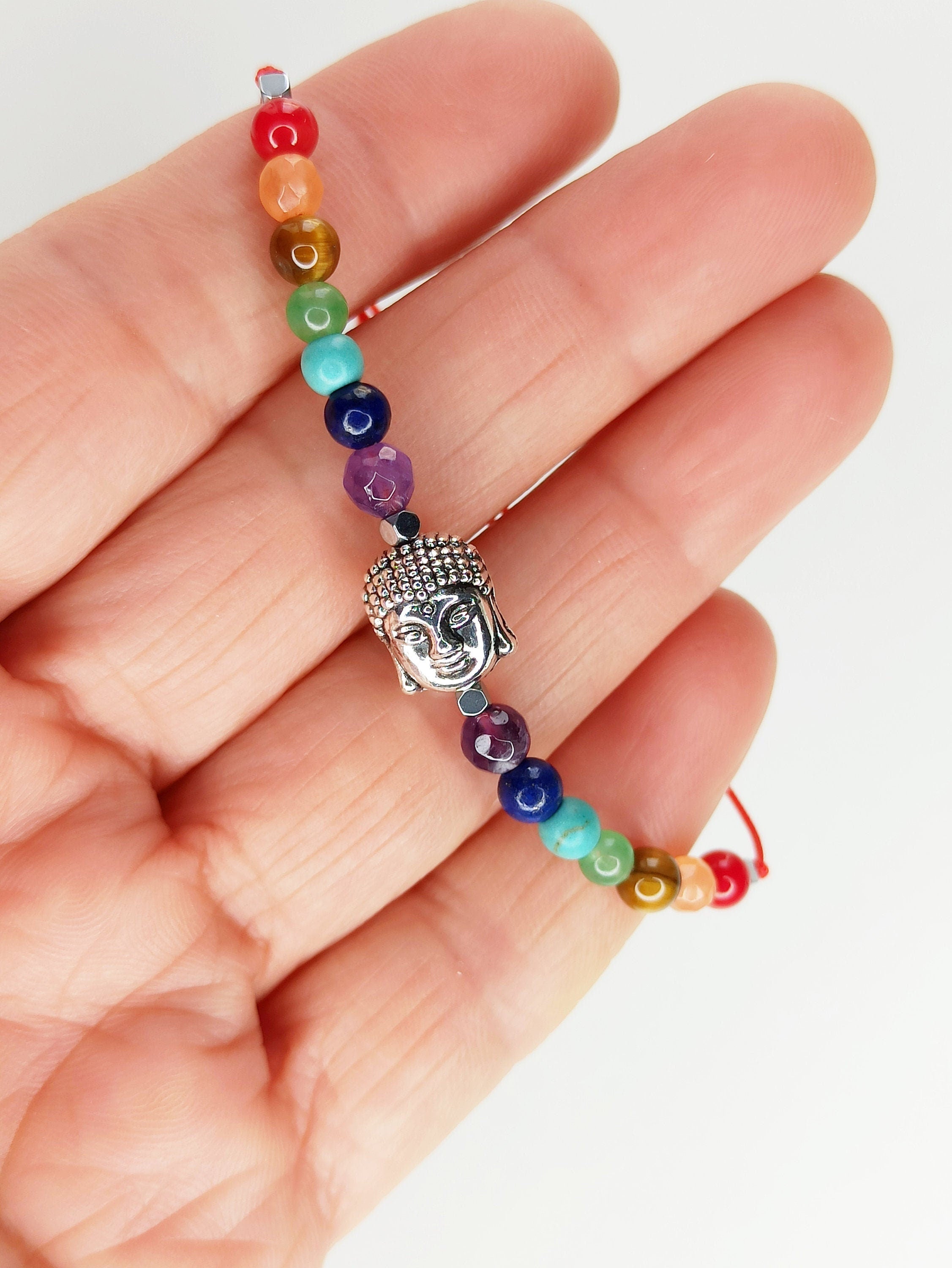 Pulsera de 7 chakras con dije de Buda en plata tibetana, ajustable y hecha a mano, presentada en una tarjeta decorativa.