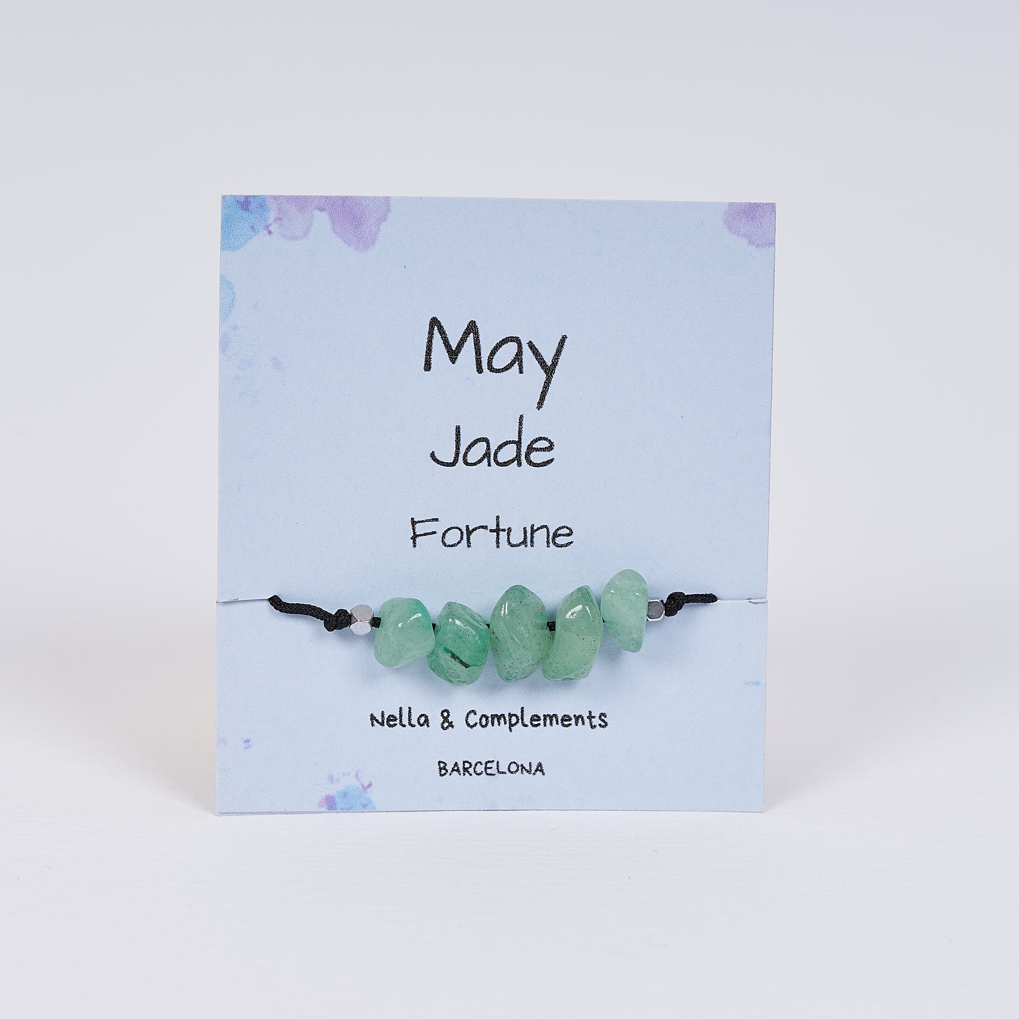 Pulsera de jade irregular de mayo, hecha a mano, con hilo negro y seis piedras de jade, presentada en una tarjeta de regalo.