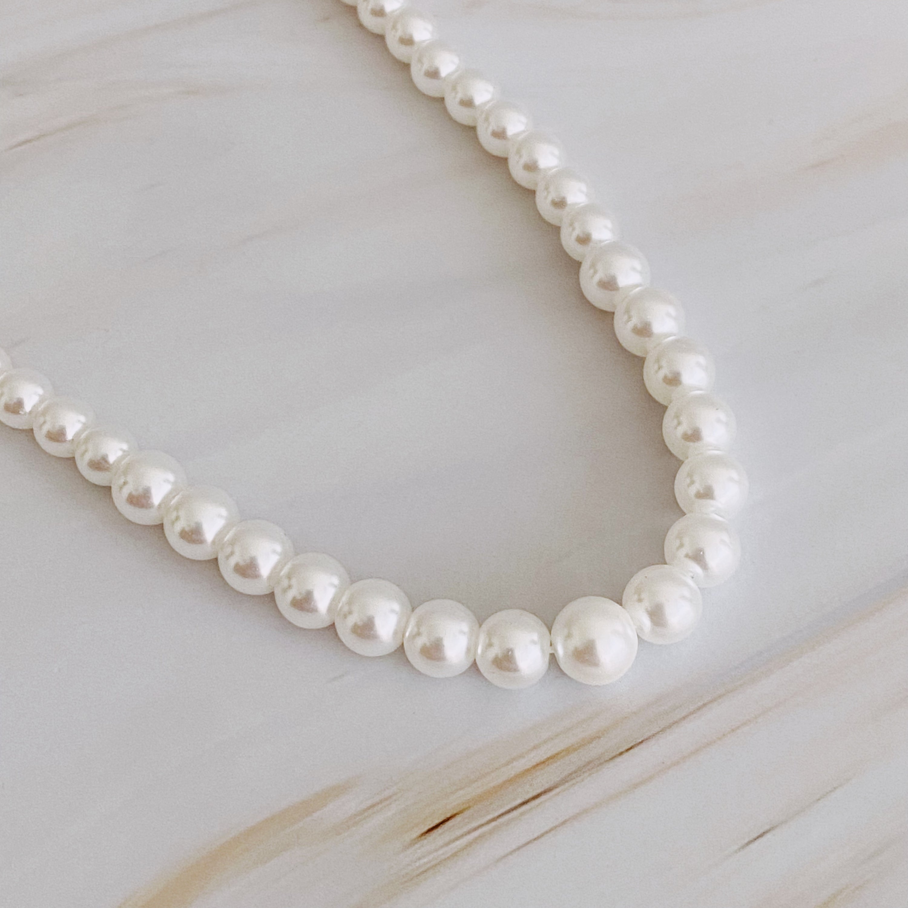 Queen Liz Graduated Pearl Necklace featuring graduated glass pearls from 4mm to 7mm with an 18k gold-plated brass closure.