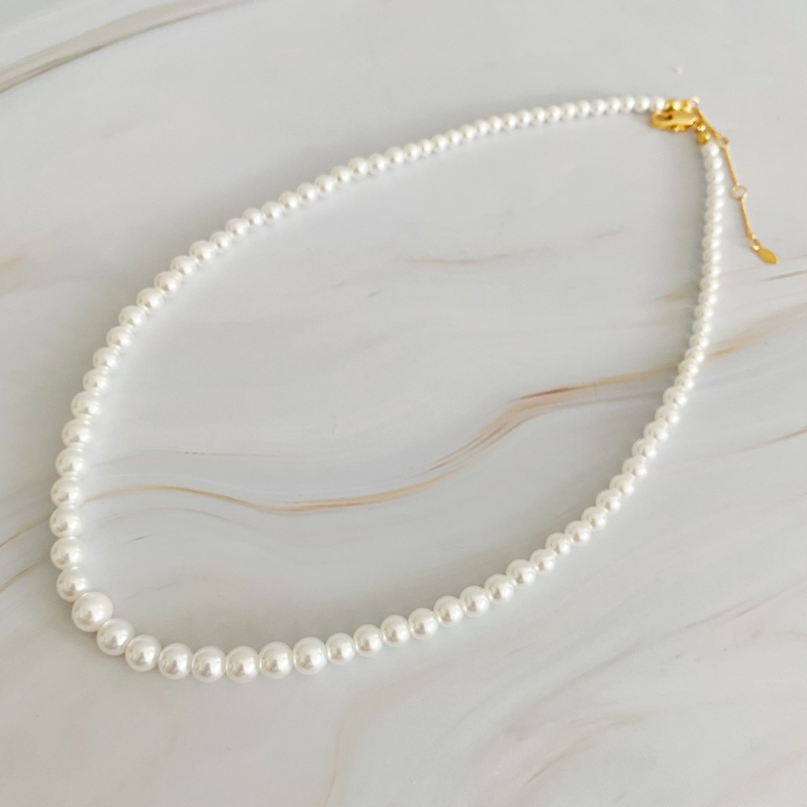 Queen Liz Graduated Pearl Necklace featuring graduated glass pearls from 4mm to 7mm with an 18k gold-plated brass closure.