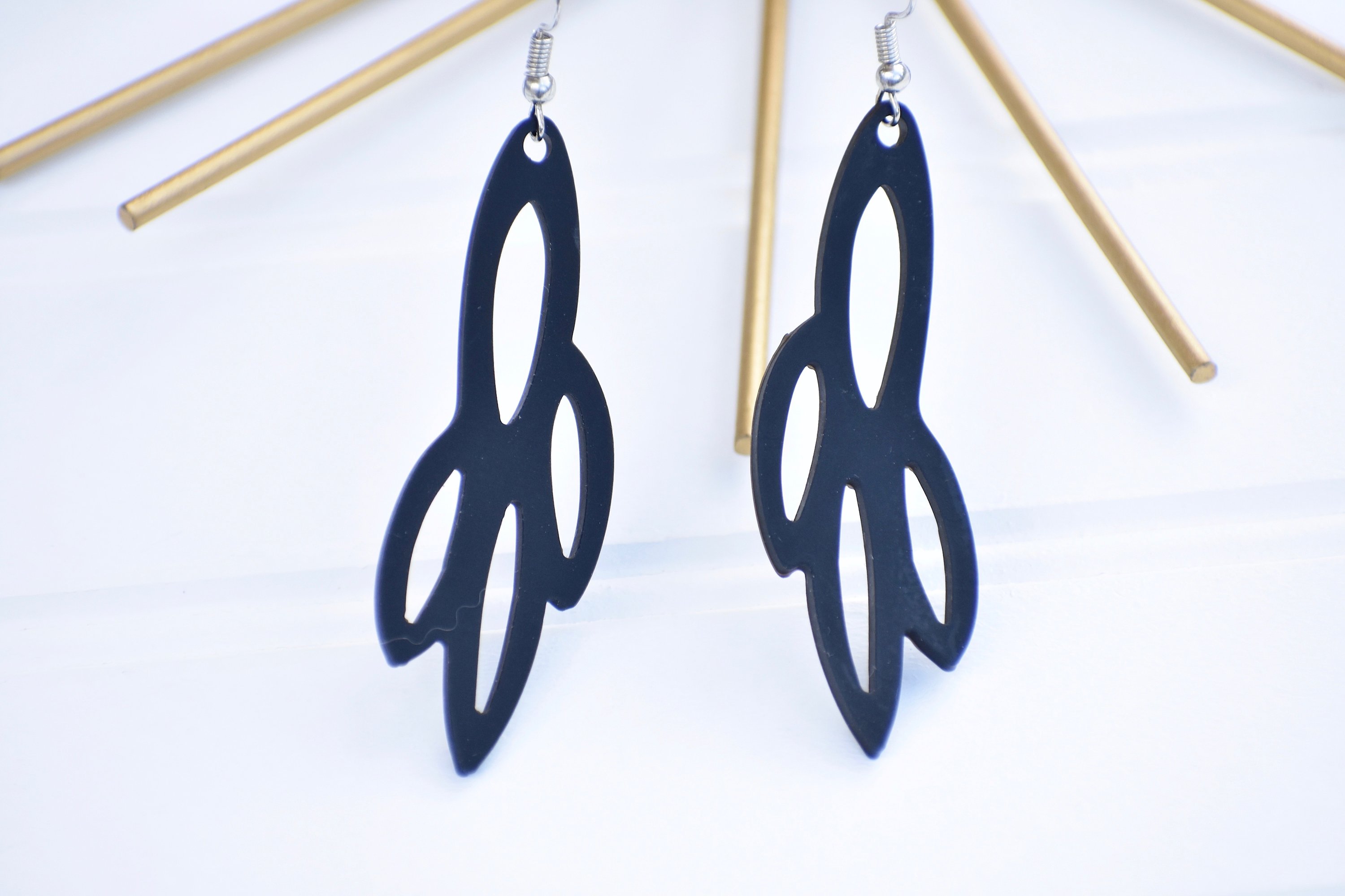 A pair of elegant Radiant Earrings displayed in a velvet pouch, showcasing their unique design and lightweight features.