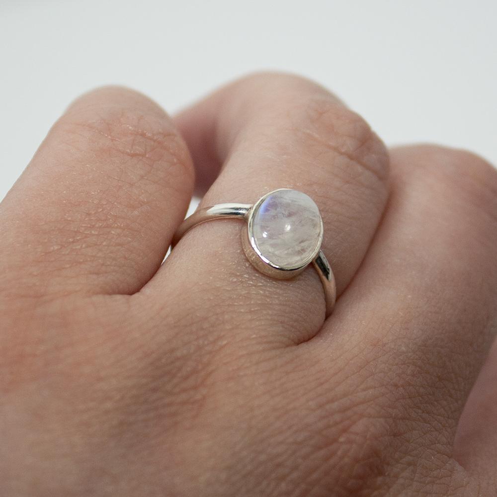 A stunning Rainbow Moonstone Open Bezel Sterling Silver Ring featuring a 9mm x 7mm oval cabochon stone set in a delicate 2mm band.