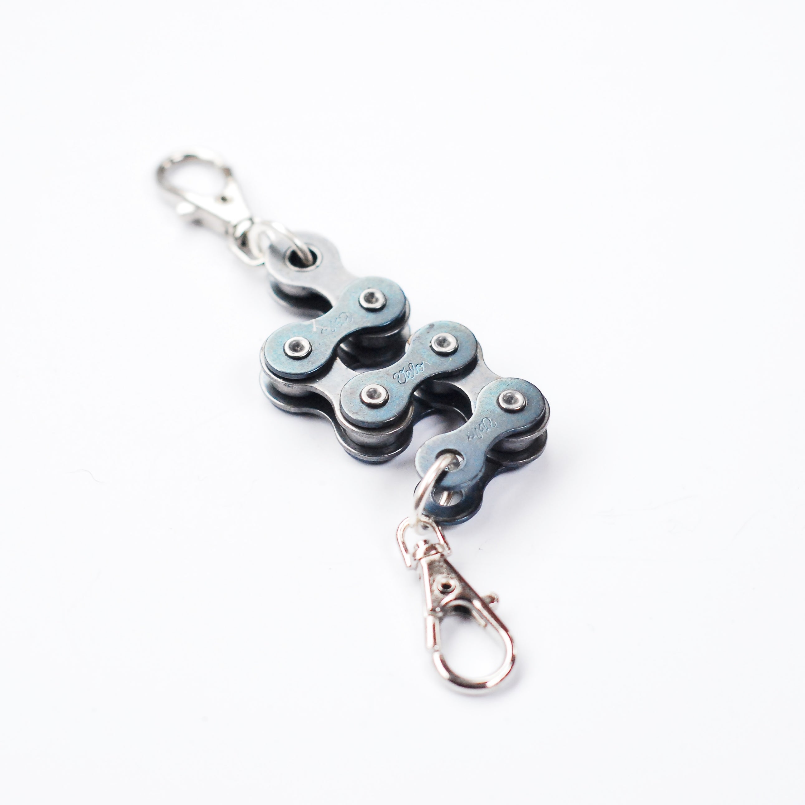 A handmade vegan keyring made from recycled bike chains, featuring a clasp and keyring for versatile use.