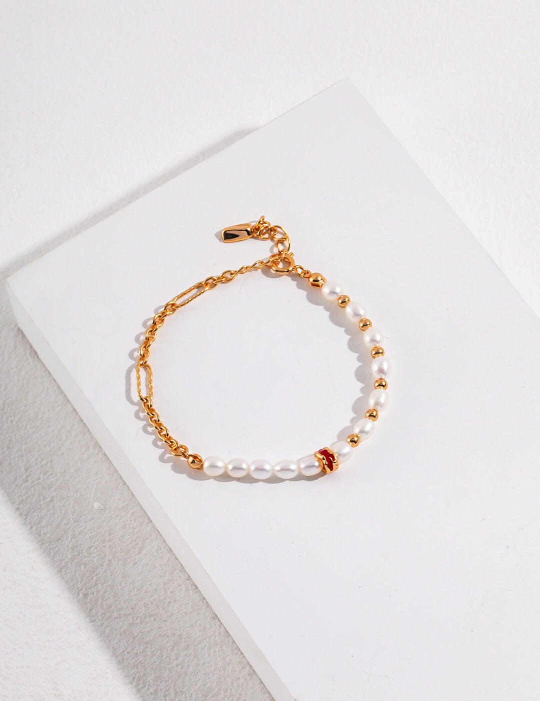 A beautifully handcrafted Red Circle Glaze Pearl Bracelet featuring genuine freshwater pearls and gold vermeil, elegantly displayed on a soft surface.