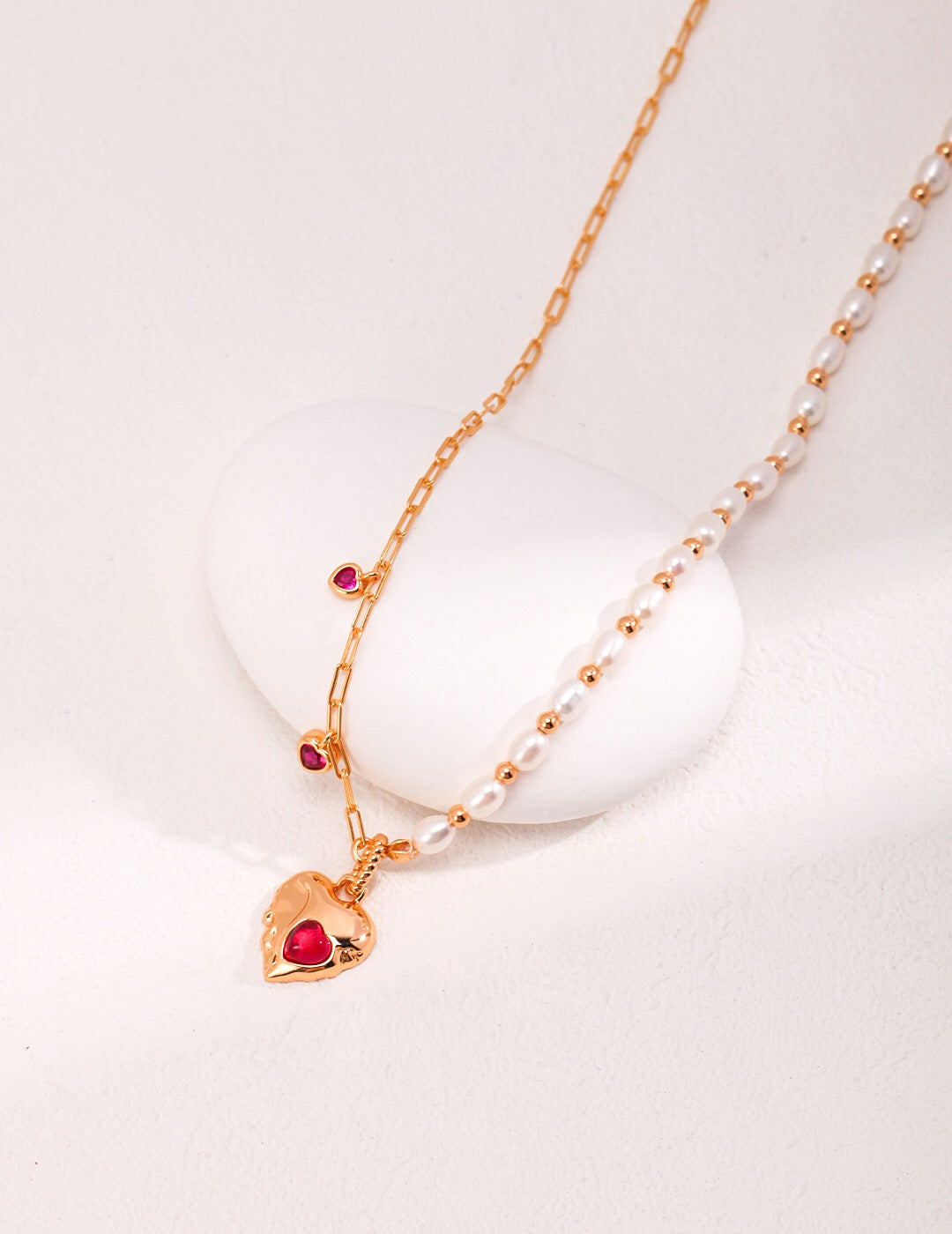 A stunning handmade necklace featuring a red corundum heart pendant and natural pearls, elegantly displayed on a soft background.