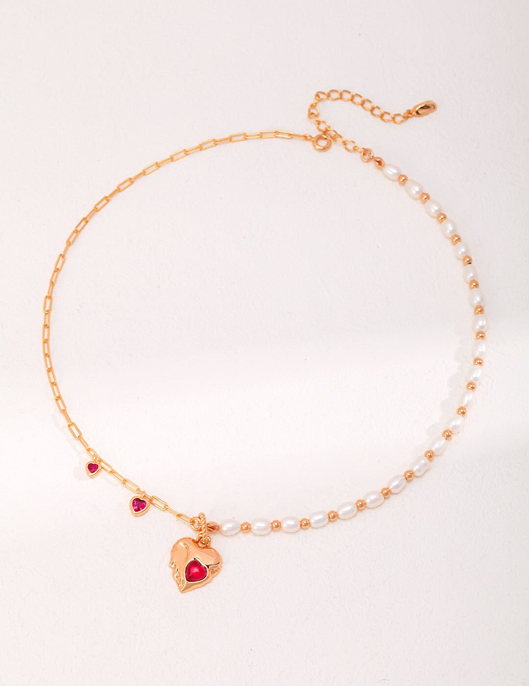 A stunning handmade necklace featuring a red corundum heart pendant and natural pearls, elegantly displayed on a soft background.