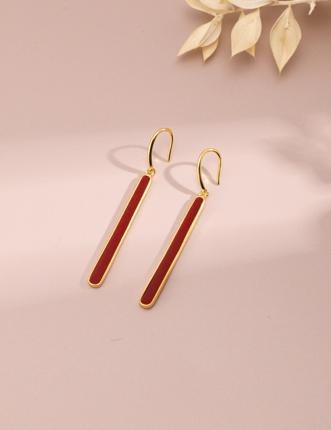 A pair of handmade red dripping glaze earrings with gold vermeil accents, showcasing a unique and elegant design.