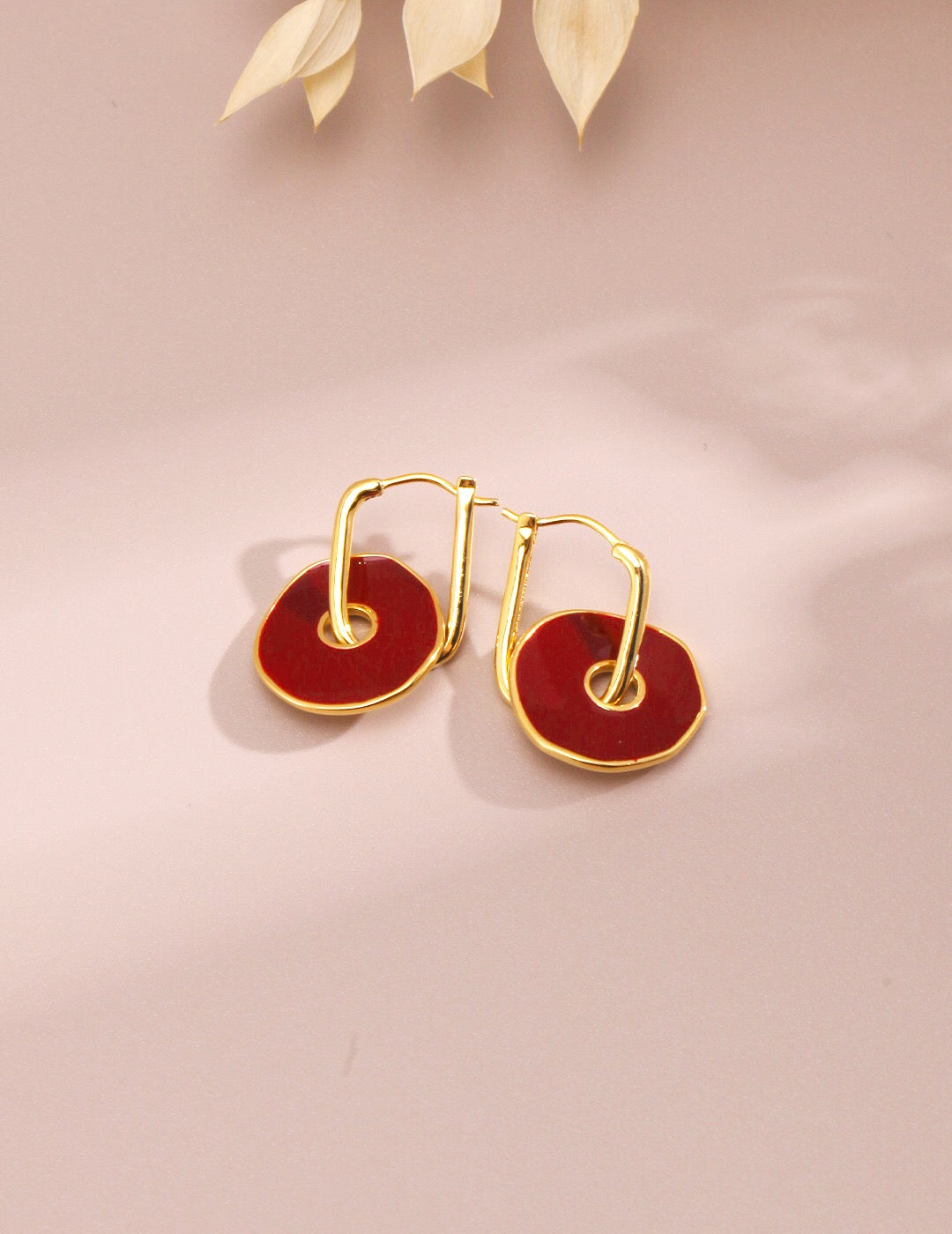 A pair of handmade red enamel earrings with gold vermeil plating, showcasing a unique design and elegant craftsmanship.