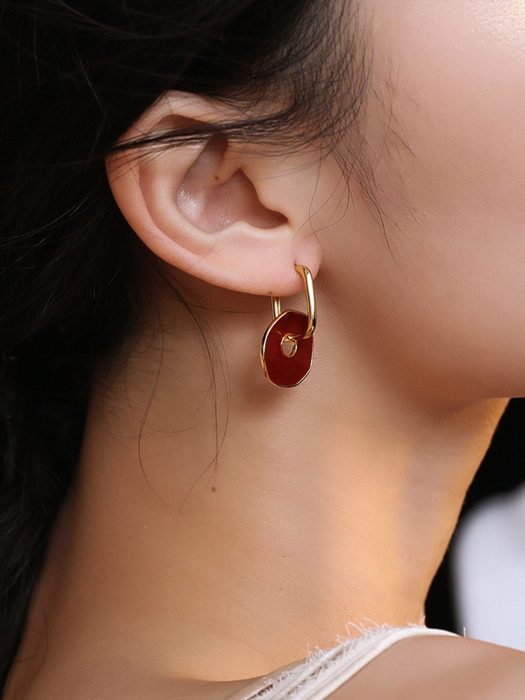 A pair of handmade red enamel earrings with gold vermeil plating, showcasing a unique design and elegant craftsmanship.