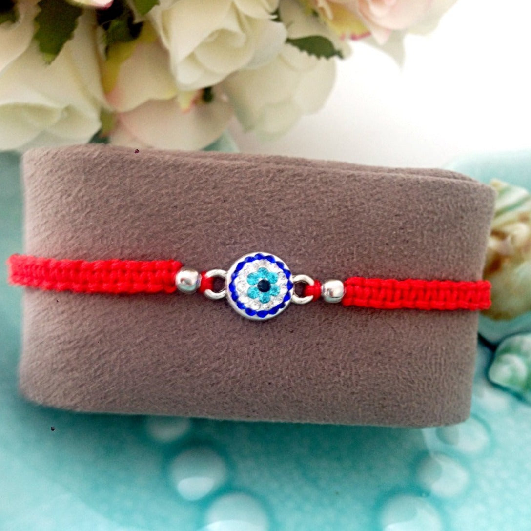 Handmade red macramé evil eye bracelet with adjustable design, featuring a protective evil eye charm.