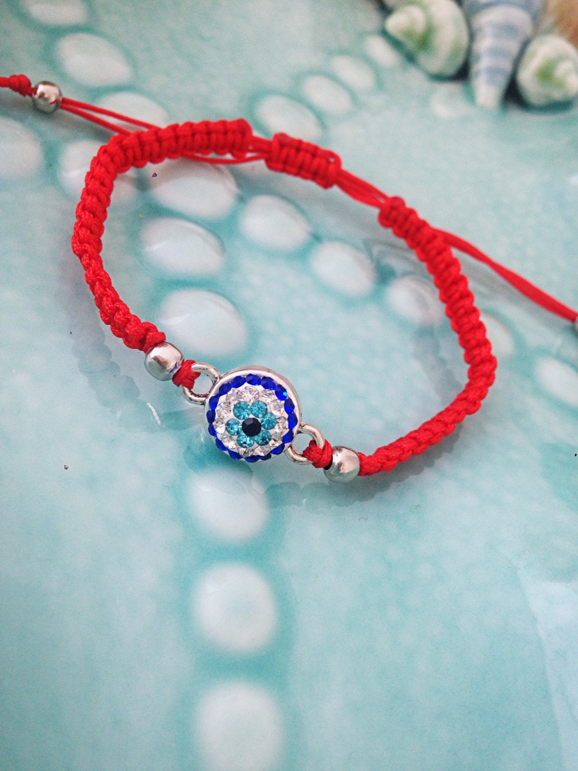 Handmade red macramé evil eye bracelet with adjustable design, featuring a protective evil eye charm.